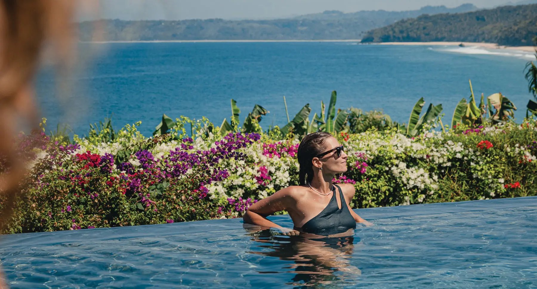 Infinity waters blur into ocean horizons while bougainvillea blooms frame this clifftop sanctuary, where tropical gardens cascade toward Sumba's pristine coastline below.