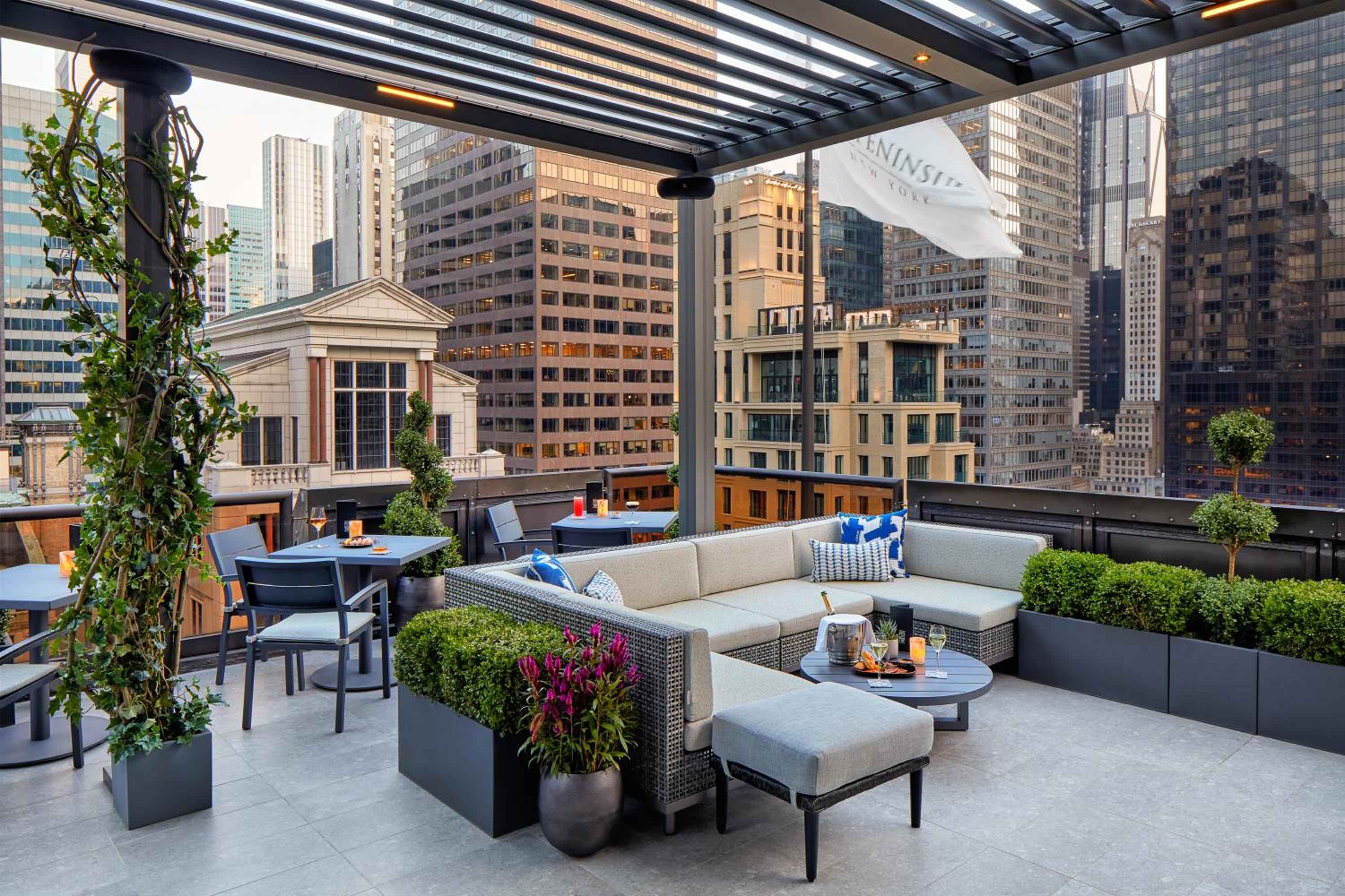 Wicker sectionals and manicured topiaries frame Manhattan's architectural symphony from this sophisticated rooftop terrace, where golden hour light warms the urban canyon below.