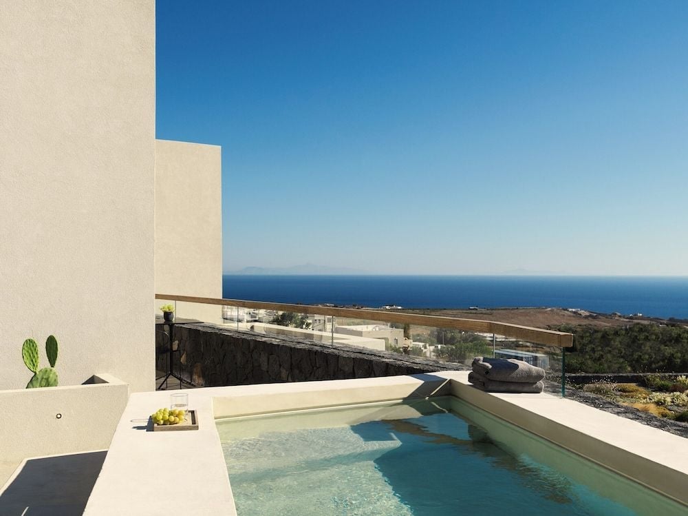 Azure waters mirror Santorini's endless sky from this pristine infinity pool, where volcanic stone walls frame sweeping Aegean vistas across sun-bleached terraces.