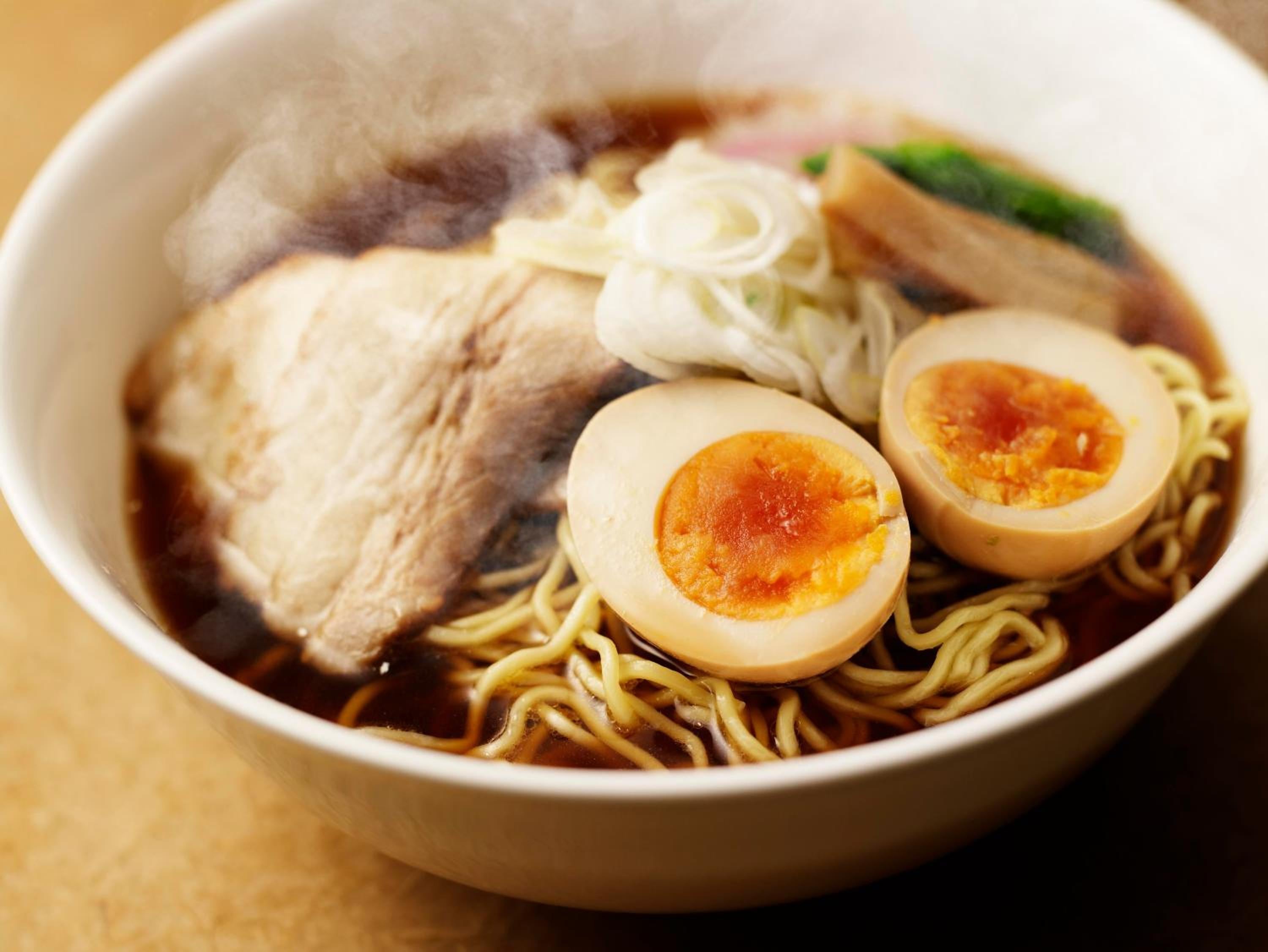 Silky ramen noodles swim in rich, amber broth alongside perfectly soft-boiled eggs and tender chashu pork at this elevated Japanese dining experience.
