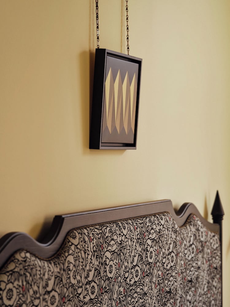 Framed knives hang like art above an ornate headboard, where medieval mystique meets modern Prague elegance in unexpected harmony.