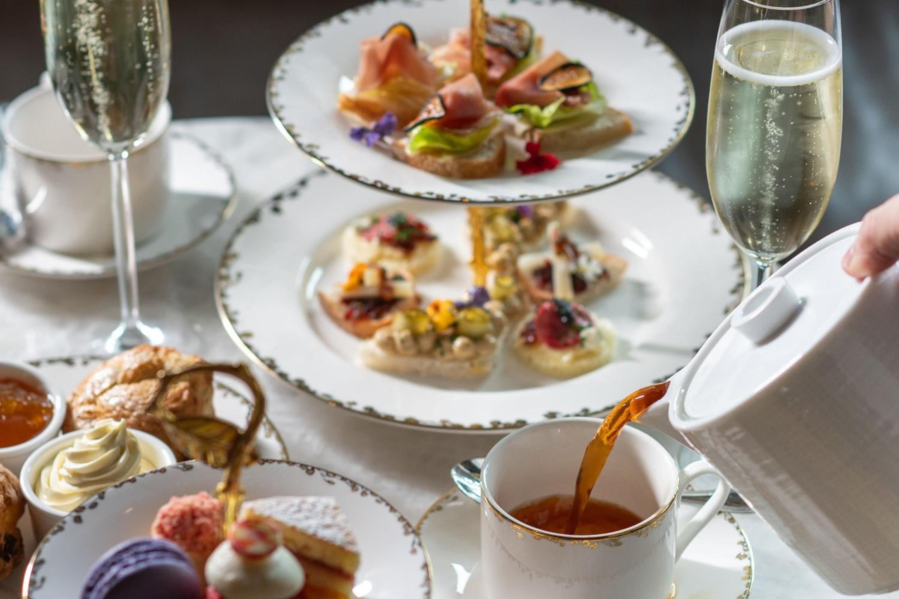 Delicate canapés and perfectly poured champagne elevate afternoon tea to an art form, where every bite delivers sophisticated flavors amid gleaming china and crystal.