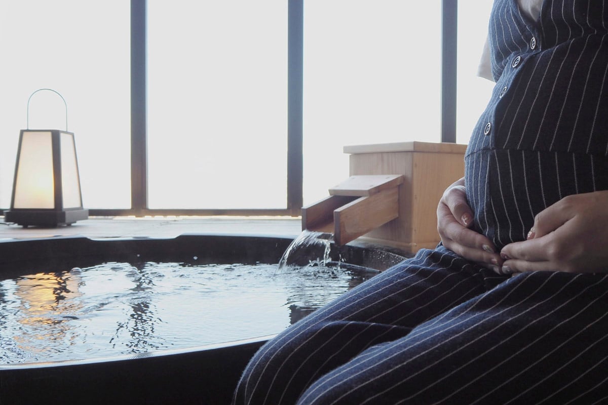 Steam rises from the hinoki cypress bath as warm light filters through shoji screens, creating an intimate sanctuary for traditional Japanese bathing rituals.