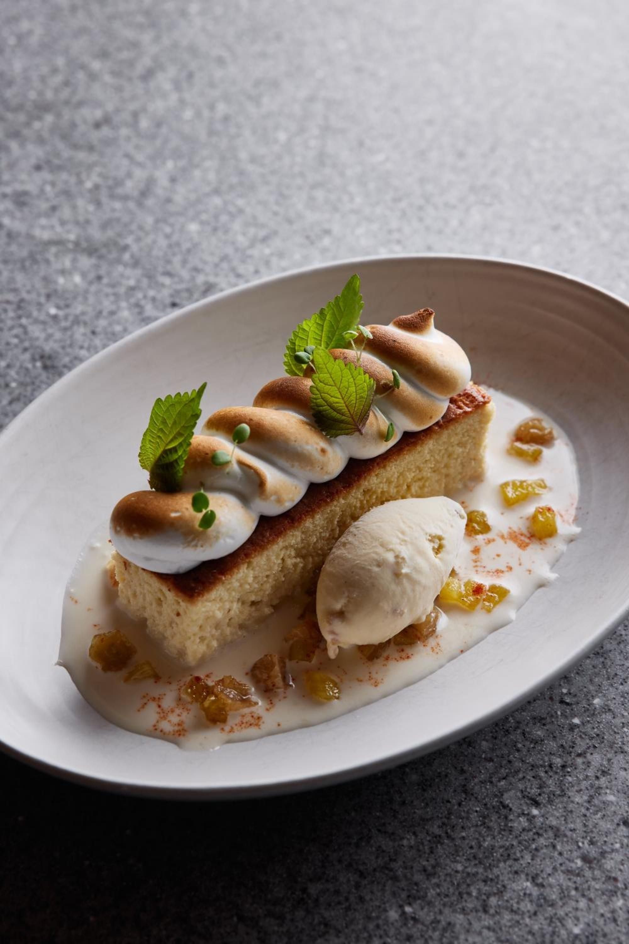 Artfully plated dessert showcases the culinary sophistication at Betsy's restaurant, where delicate meringues and golden raisins transform simple cake into edible art.