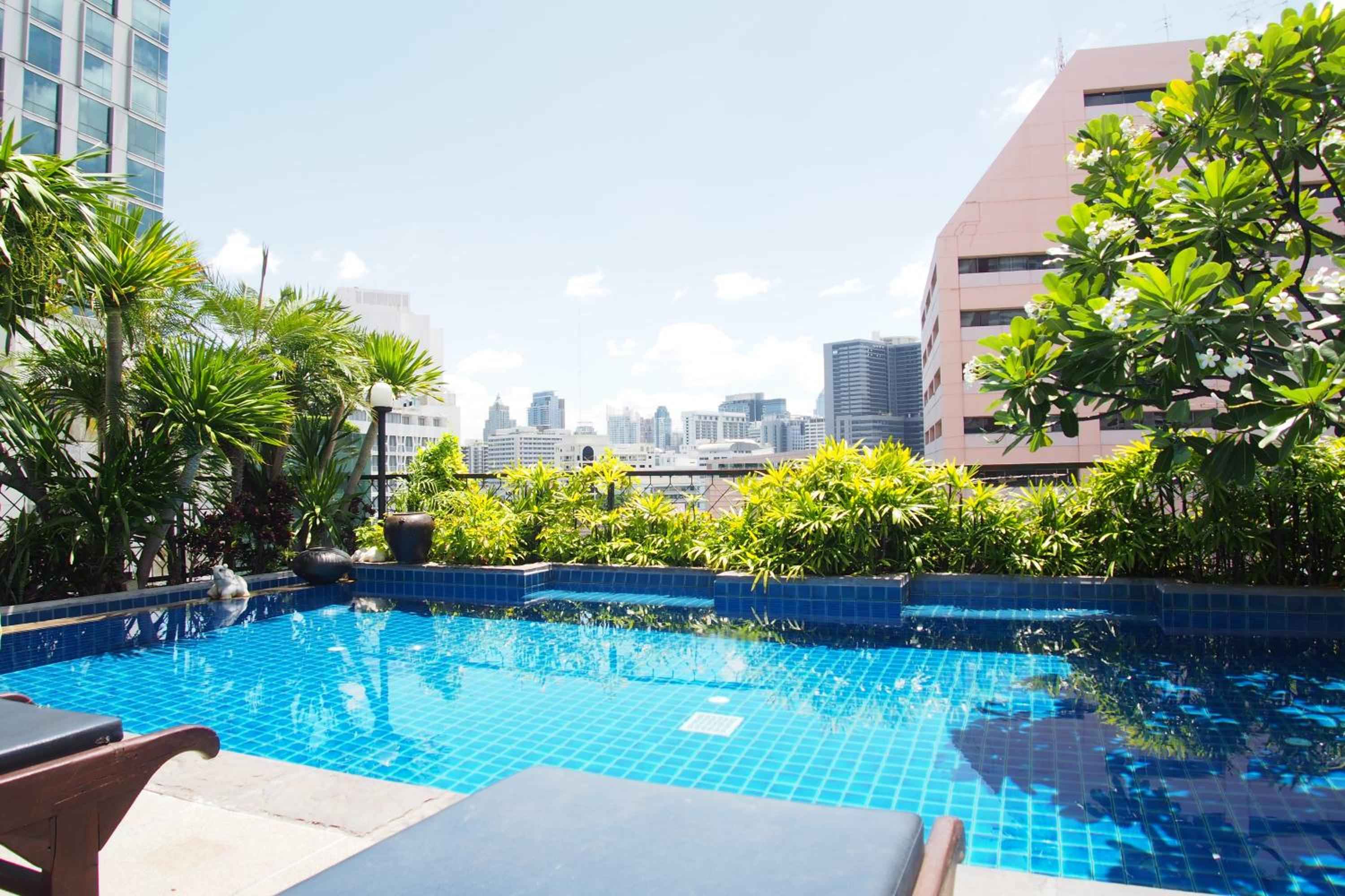 Azure waters shimmer against Bangkok's gleaming skyline from this intimate rooftop retreat, where tropical plantings frame infinity edges and city energy feels worlds away.