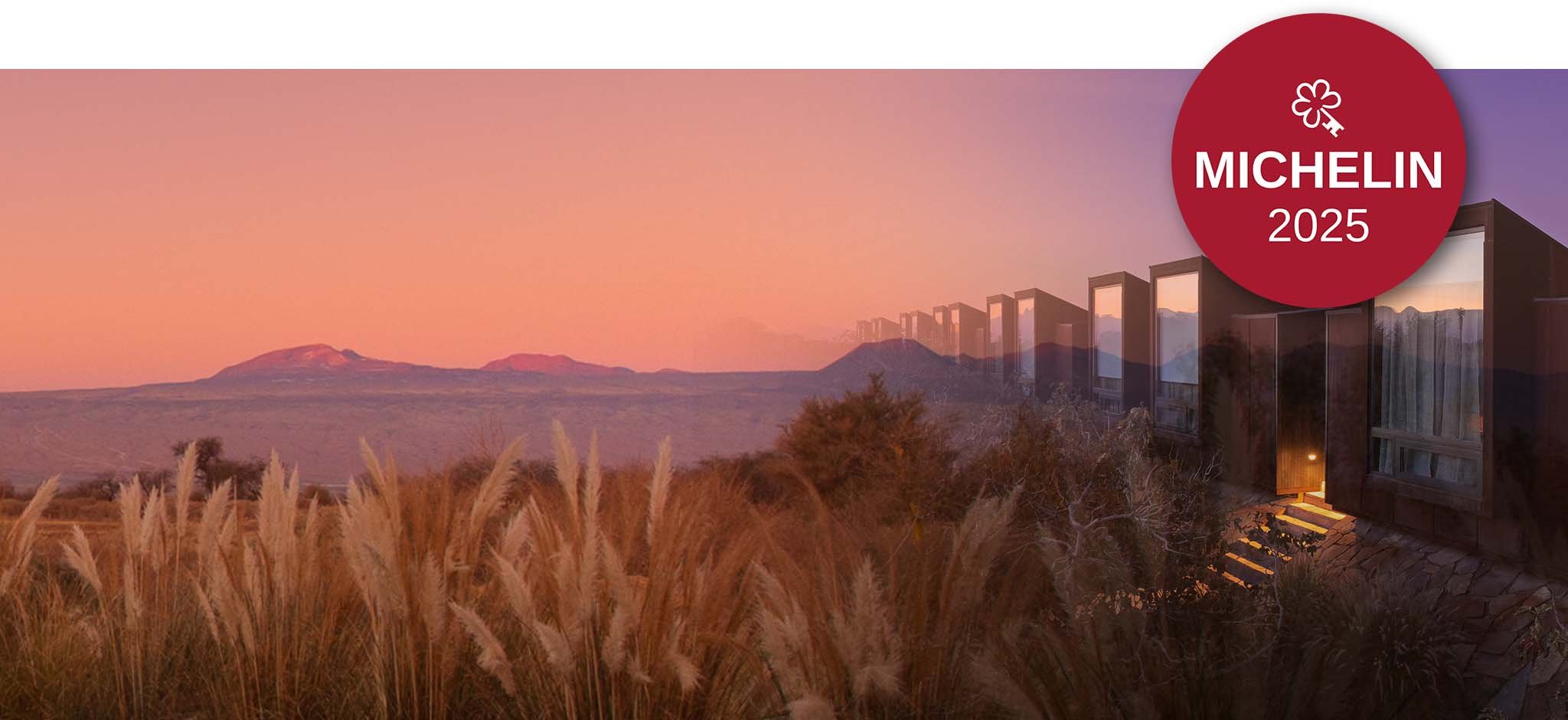 Golden hour bathes the desert lodge in warm light as pampas grass sways against the dramatic Atacama landscape and distant volcanic peaks.