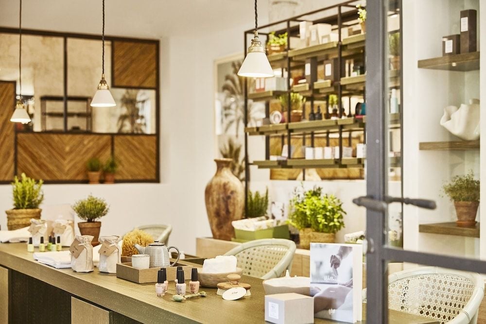 Natural skincare treasures and artisanal wellness products line rustic wooden shelves in the spa's serene retail sanctuary, where woven baskets and verdant plants create an organic, apothecary atmosphere.