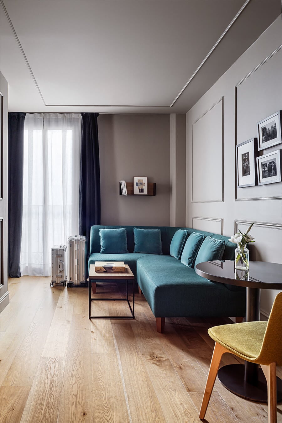 Teal velvet sectional and warm oak floors create an inviting retreat, where linear ceiling details and curated gallery walls reflect Madrid's contemporary design sensibility.
