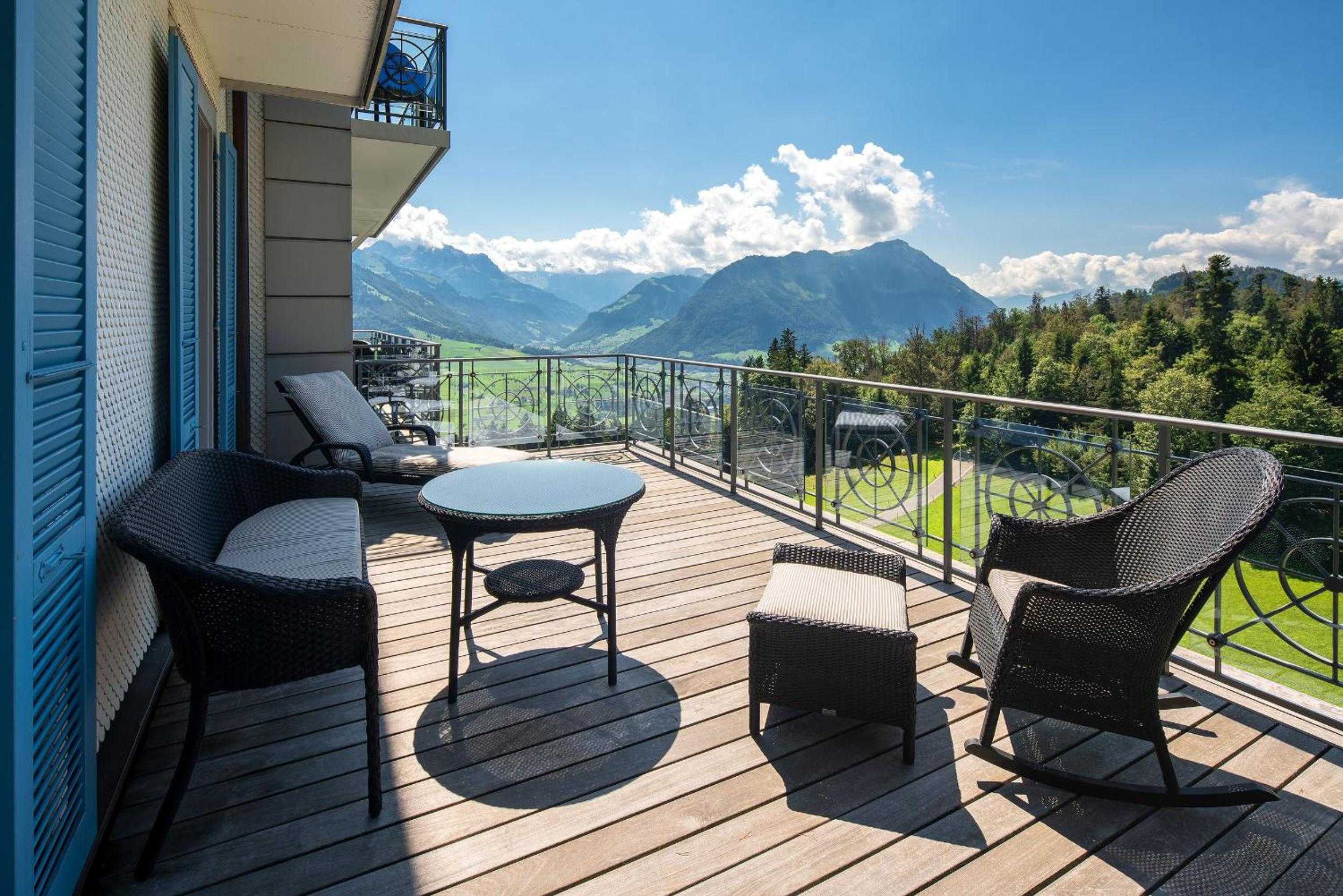 Wicker chairs and weathered decking frame sweeping Alpine vistas from this mountain-facing terrace, where morning coffee tastes better against Switzerland's dramatic peaks.
