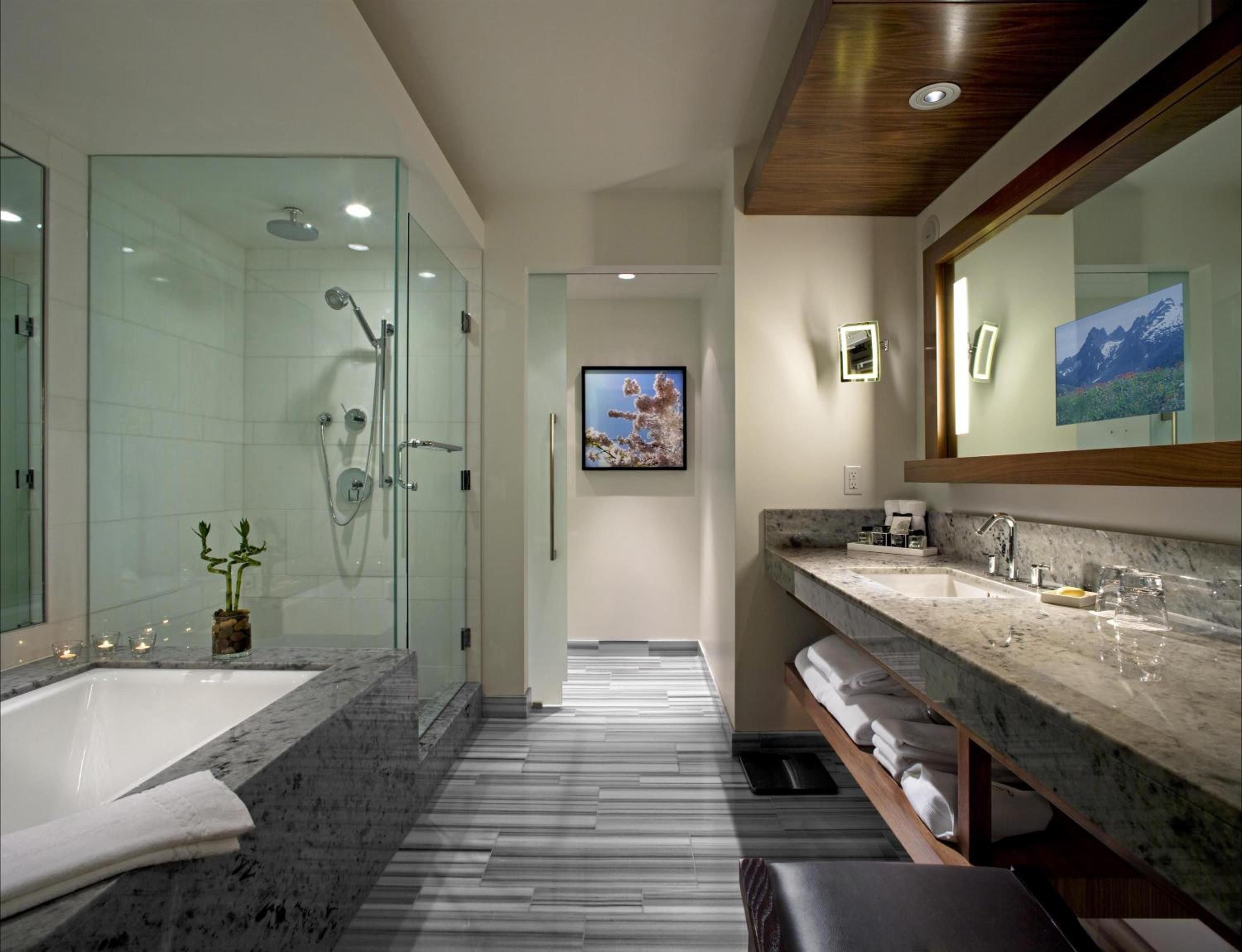 Marble countertops gleam beneath warm wood accents while glass-enclosed showers create a spa-like sanctuary with mountain views reflected in oversized mirrors.