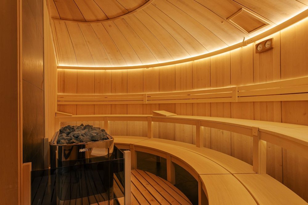 Curved cedar benches and warm LED strips create an intimate cocoon in this barrel-style sauna, where volcanic stones promise authentic Finnish heat therapy.