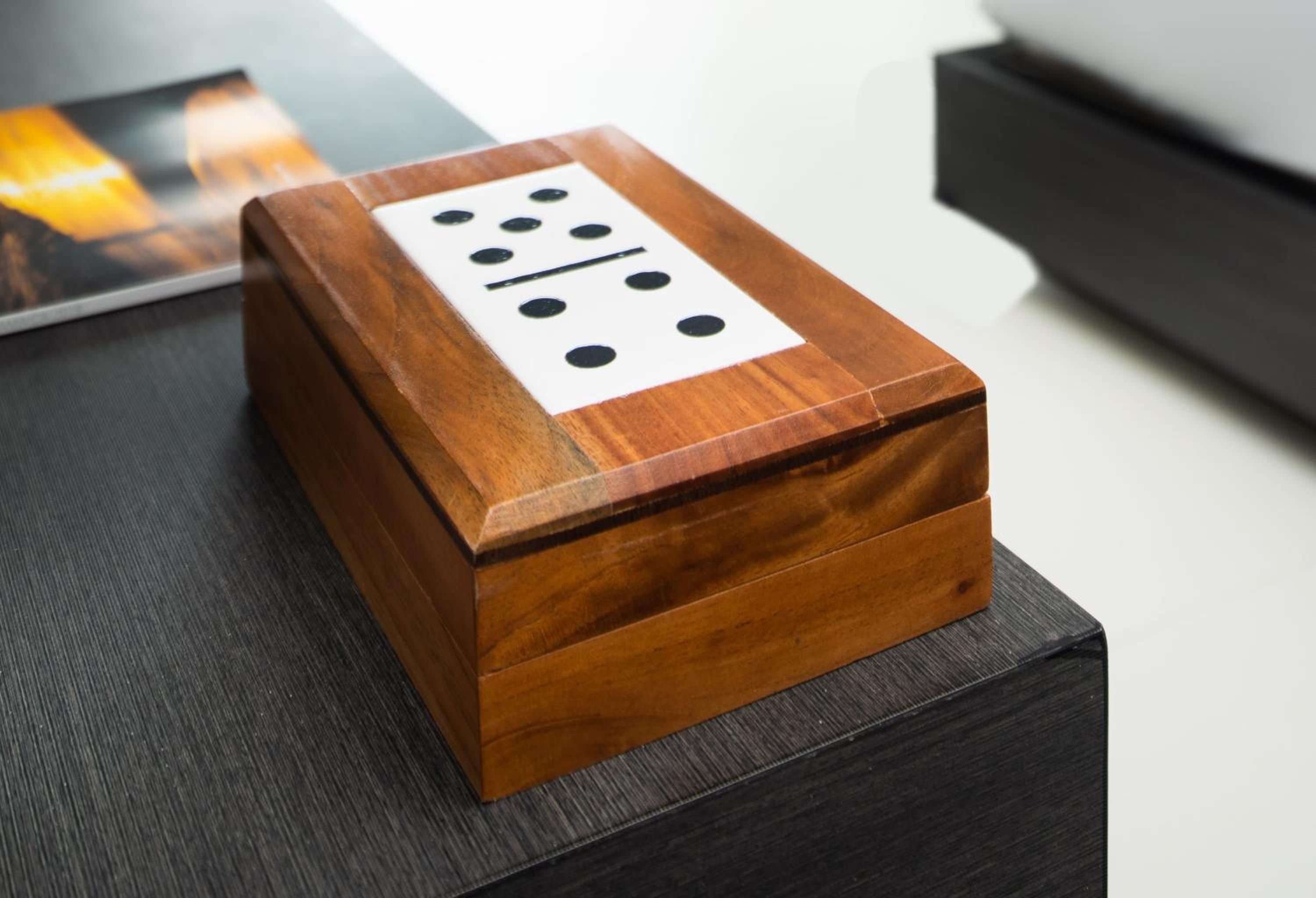 Handcrafted wooden dominoes rest in a polished teak box, embodying the resort's Caribbean heritage and attention to artisanal details that elevate leisure moments.