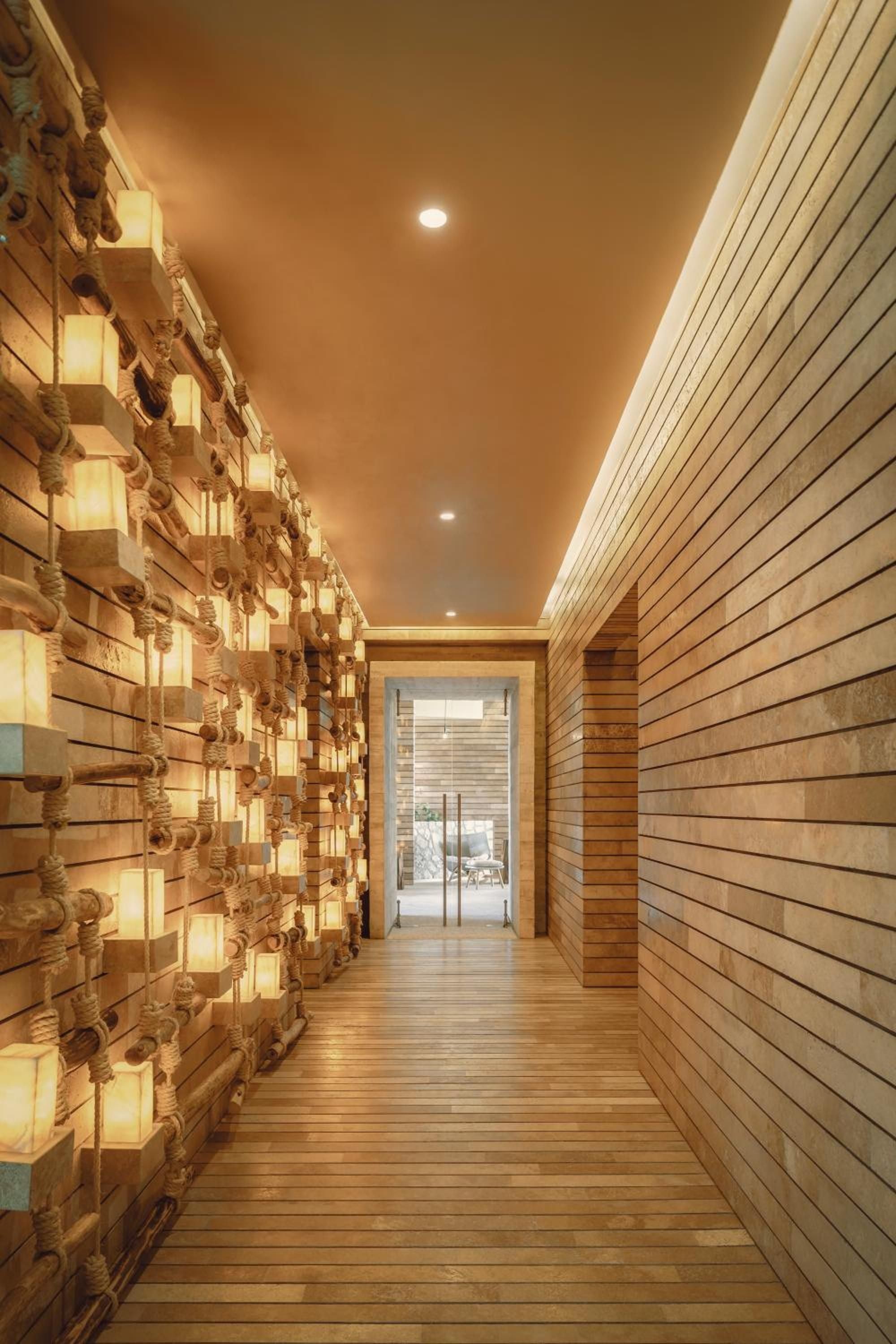 Warm cedar walls and illuminated sculptural elements create a meditative corridor, where natural wood textures and golden lighting transform a simple passageway into sensory poetry.