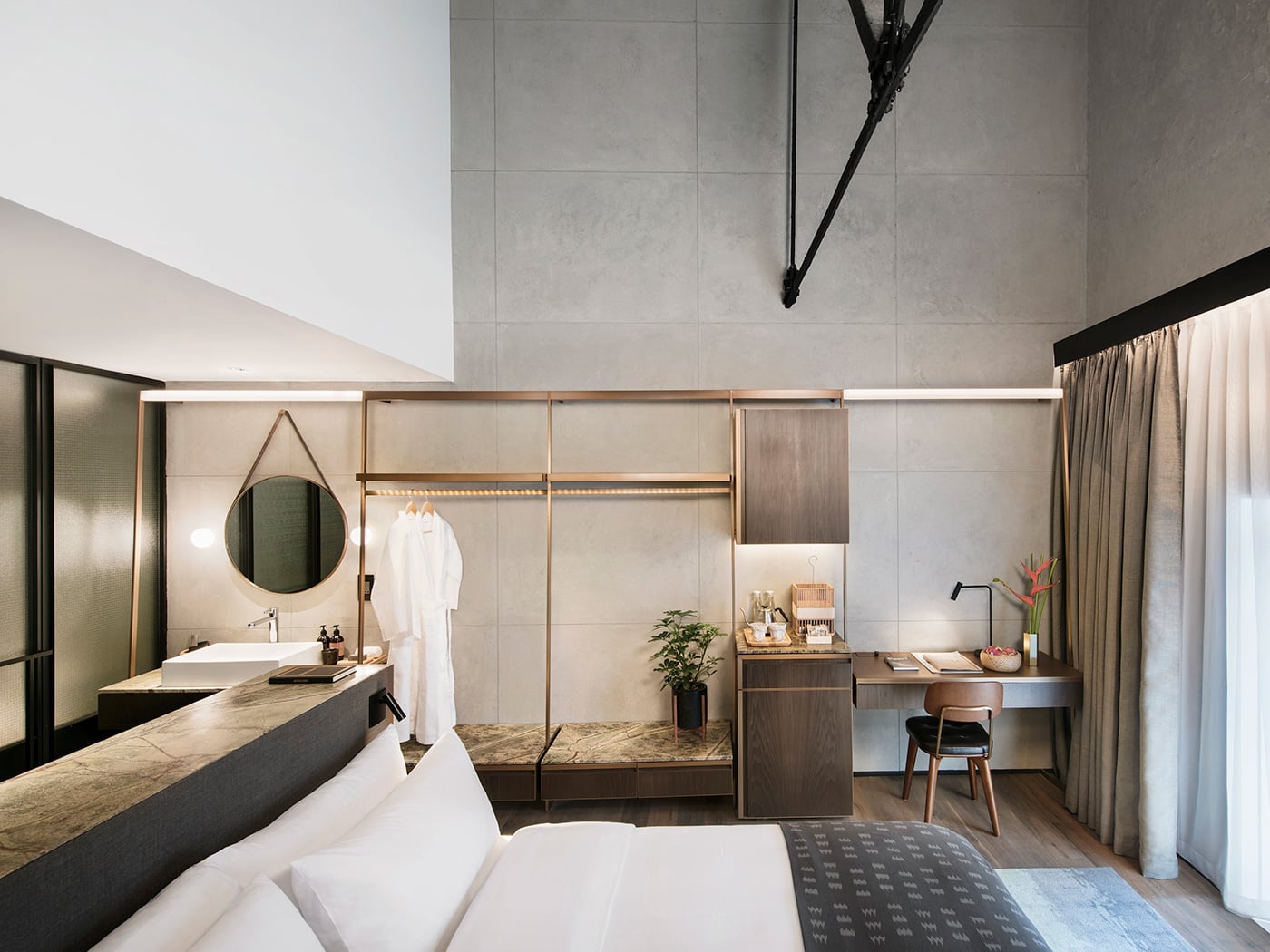 Industrial concrete meets warm wood in thoughtfully designed suites where exposed beams frame integrated wardrobes, vintage-inspired furnishings, and an open bathroom concept.