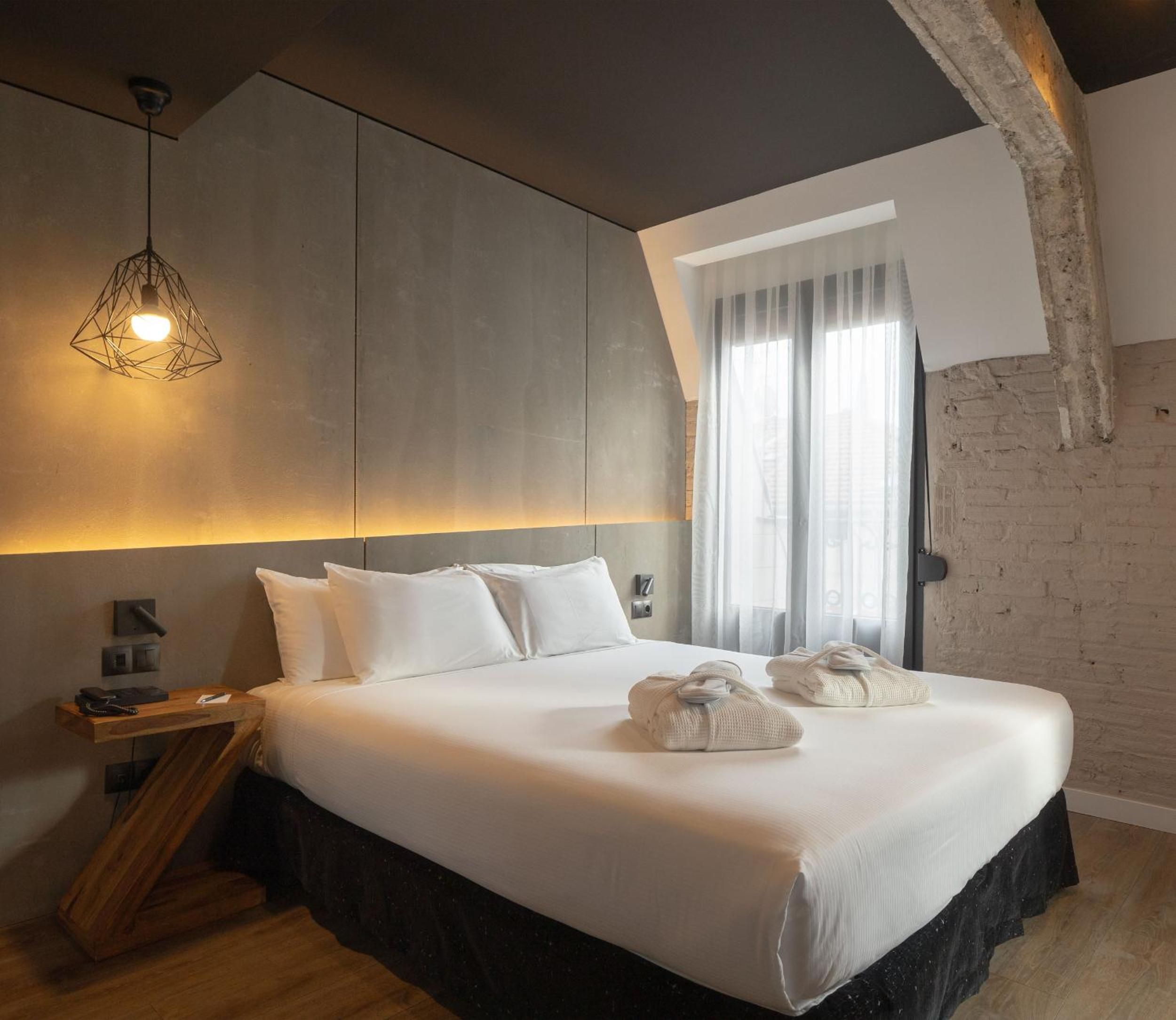 Exposed stone arches meet sleek geometric lighting in this thoughtfully designed guest room, where industrial heritage blends seamlessly with contemporary comfort and warm ambient lighting.