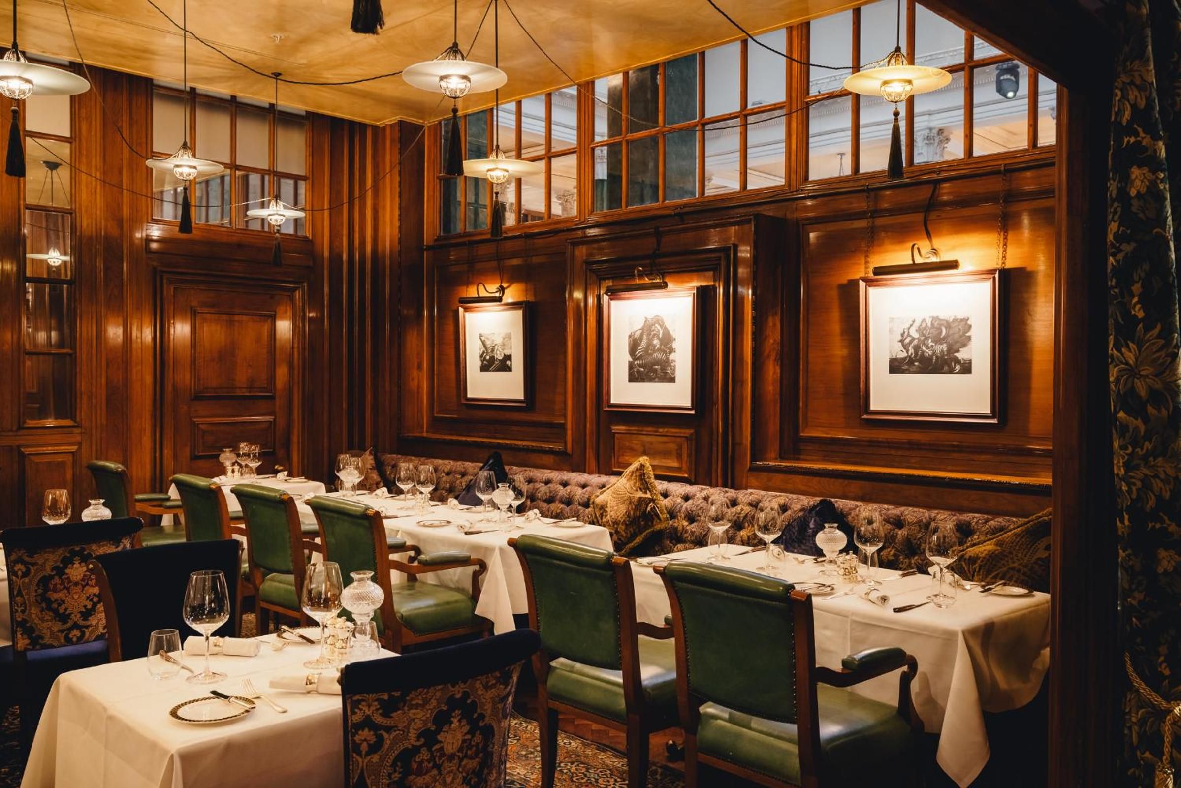 Rich mahogany paneling and forest-green leather banquettes create an intimate dining sanctuary, where crystal decanters catch the glow of brass picture lights.