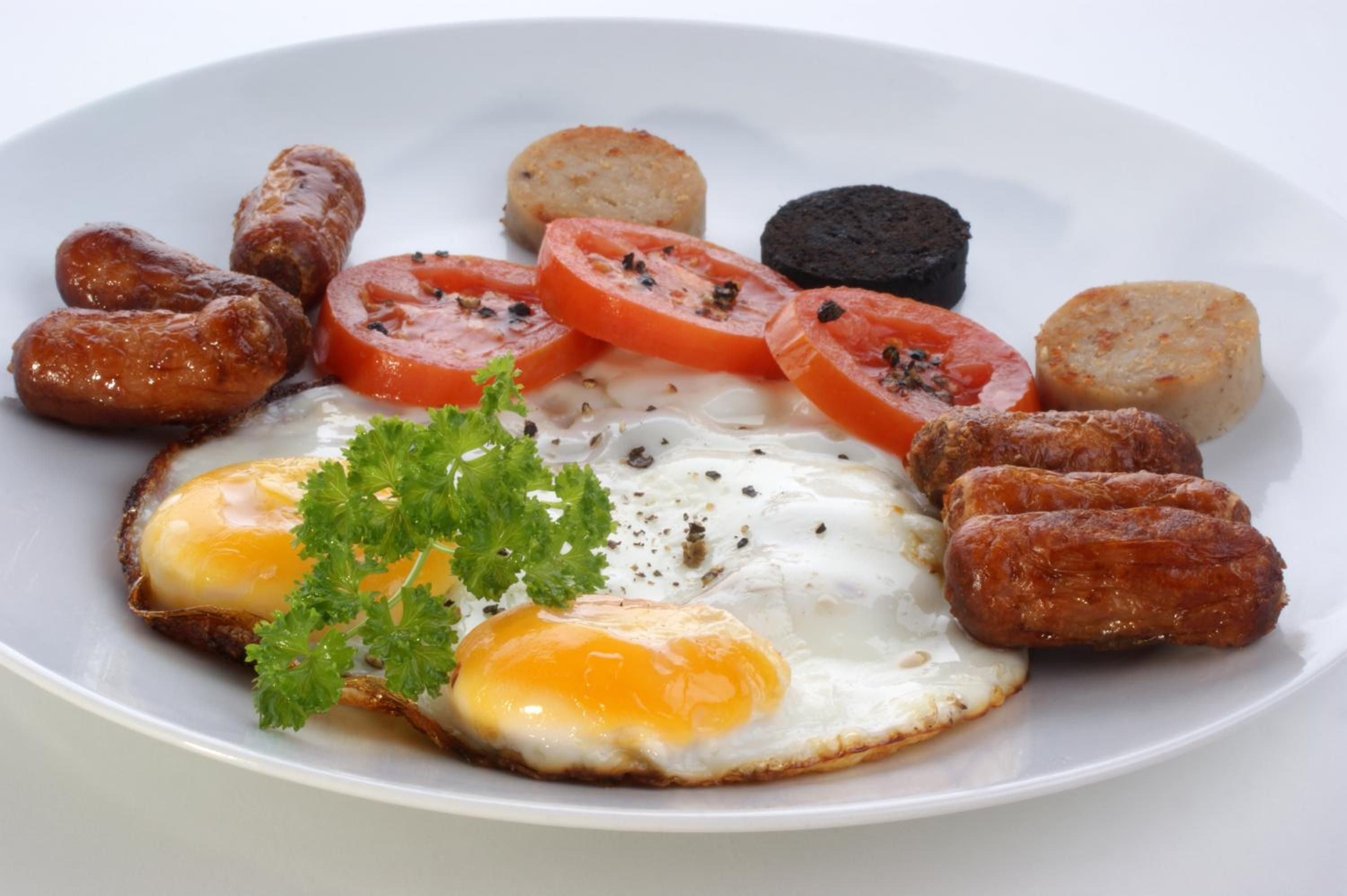 Golden-yolked eggs anchor a hearty Irish breakfast featuring crispy sausages, grilled tomatoes, and black pudding—comfort food executed with genuine care and traditional flair.