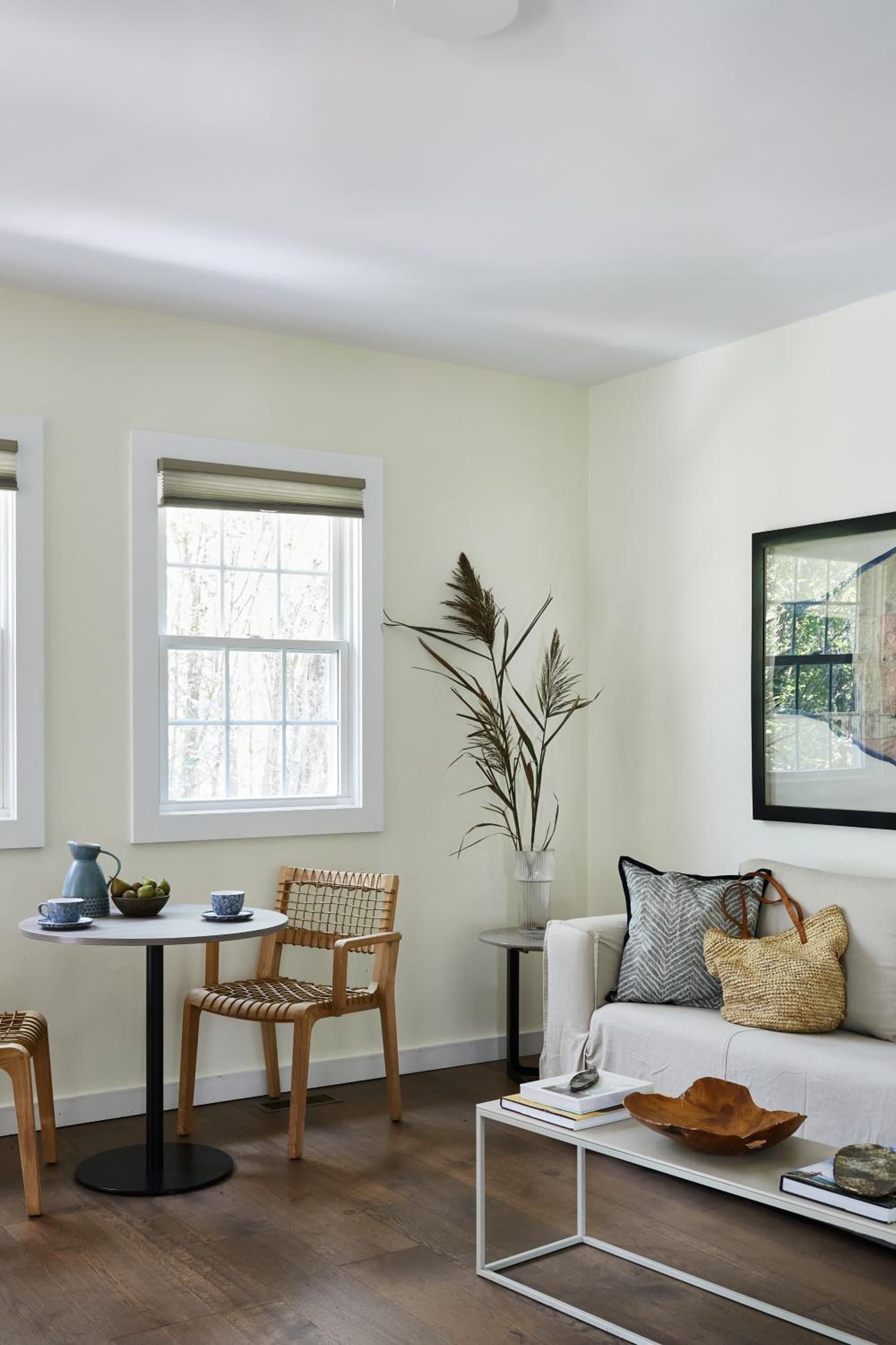 Woven chairs and natural textures create an intimate corner where morning light filters through plantation shutters, inviting quiet moments with coffee and contemplation.