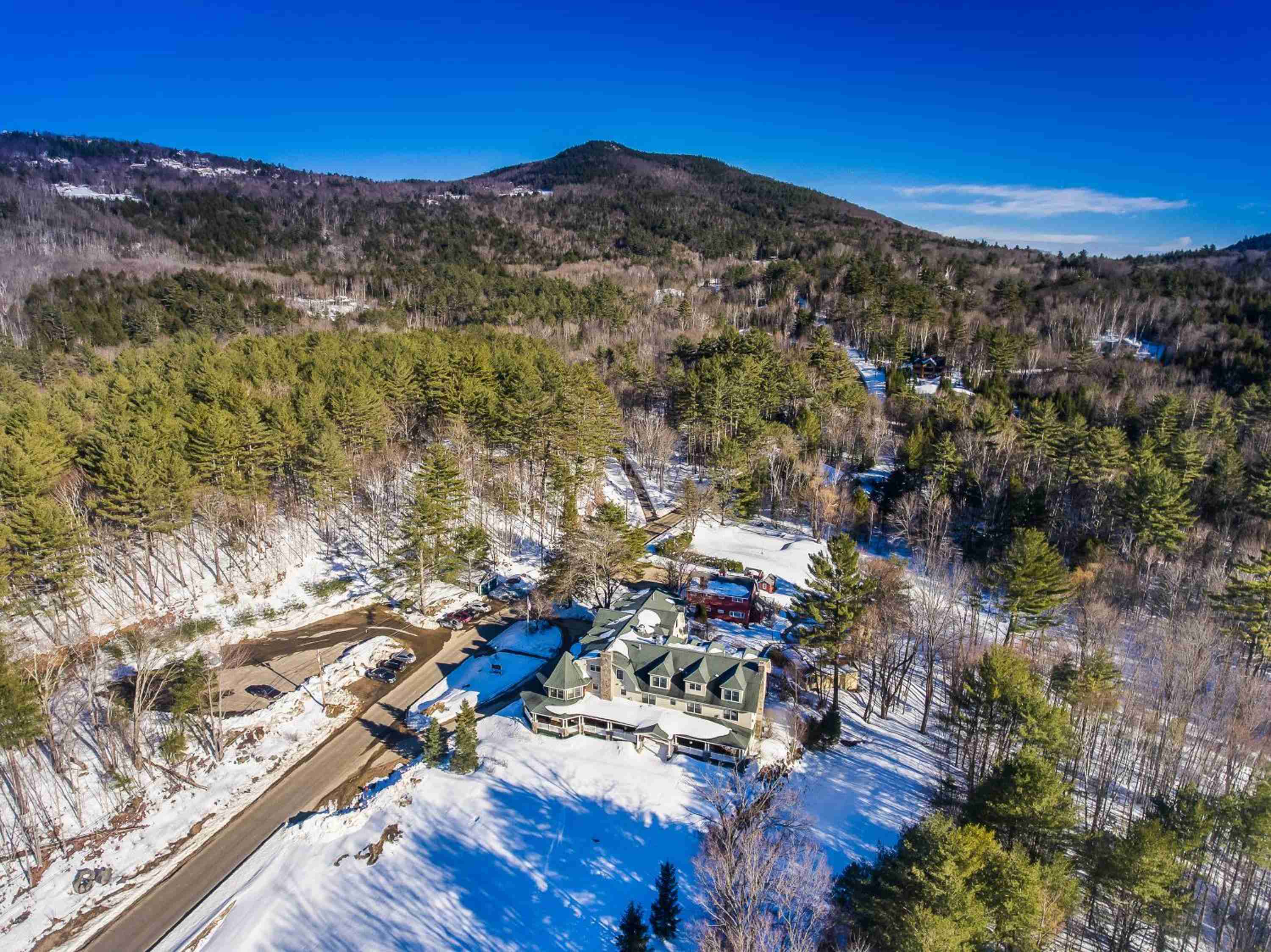 Nestled in snow-dusted New Hampshire mountains, this intimate retreat commands sweeping valley views where evergreens meet rolling peaks under brilliant blue skies.