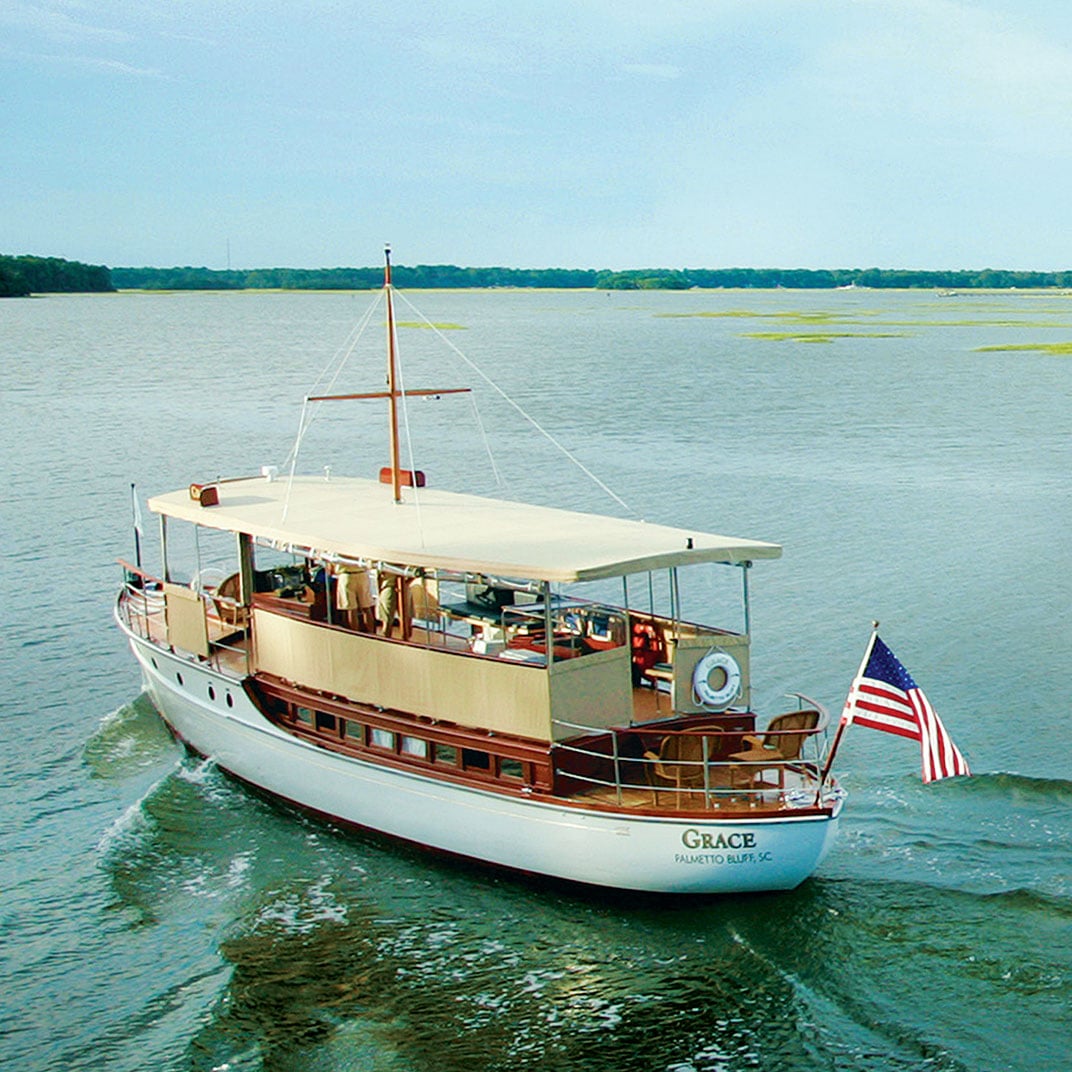 Classic yacht Grace glides through Palmetto Bluff's pristine waters, her gleaming white hull and mahogany details embodying the Lowcountry's timeless maritime elegance.