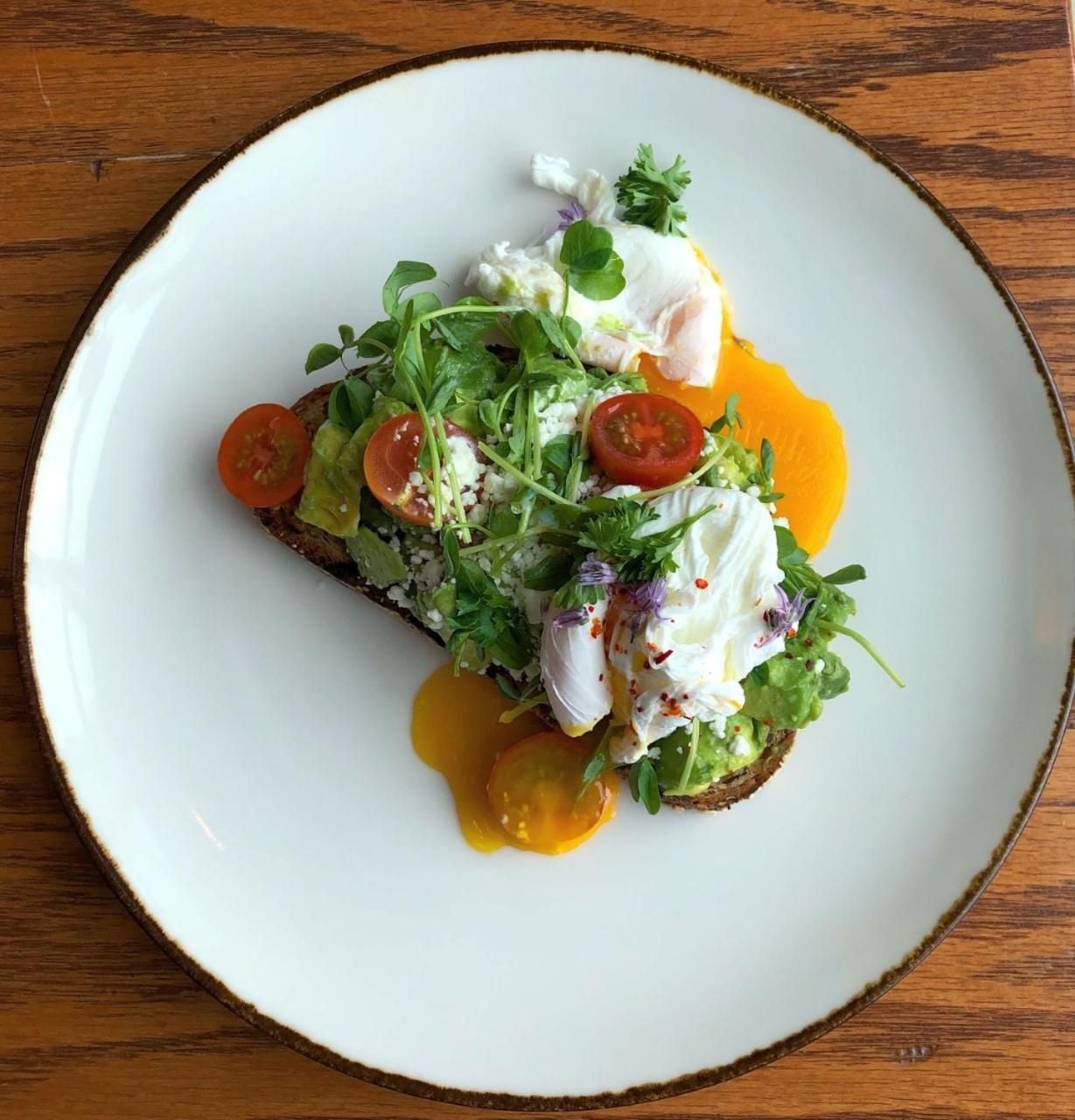 Artfully plated avocado toast crowned with perfectly poached eggs and cherry tomatoes showcases the hotel's commitment to elevated breakfast fare and Instagram-worthy presentation.