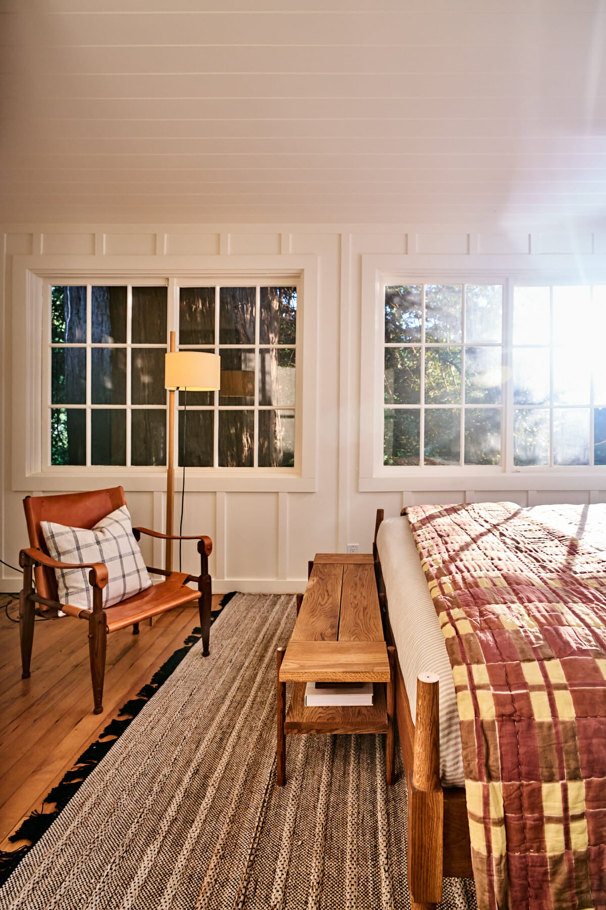 Rustic wooden furniture and handcrafted quilts create an intimate reading nook where morning light filters through gridded windows, revealing Dawn Ranch's commitment to authentic craftsmanship.