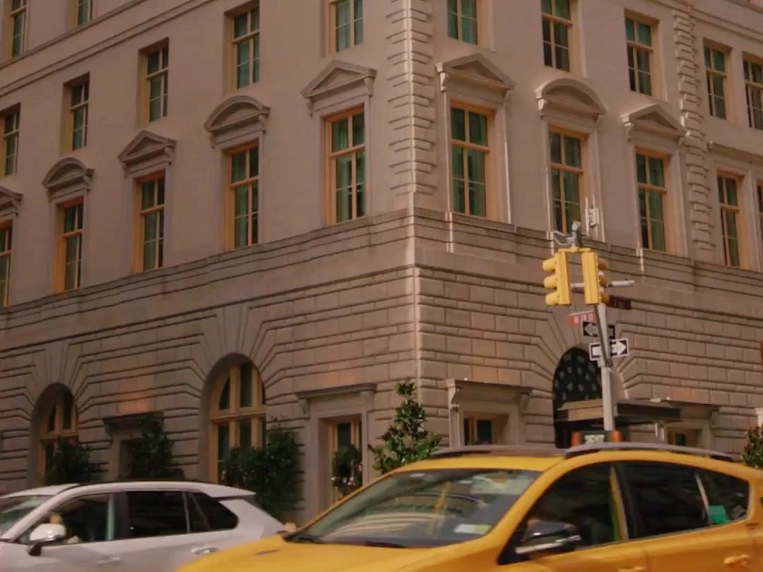 Classic limestone façade catches golden hour light while yellow taxis blur past—quintessential Manhattan elegance where refined architecture meets the city's restless energy.