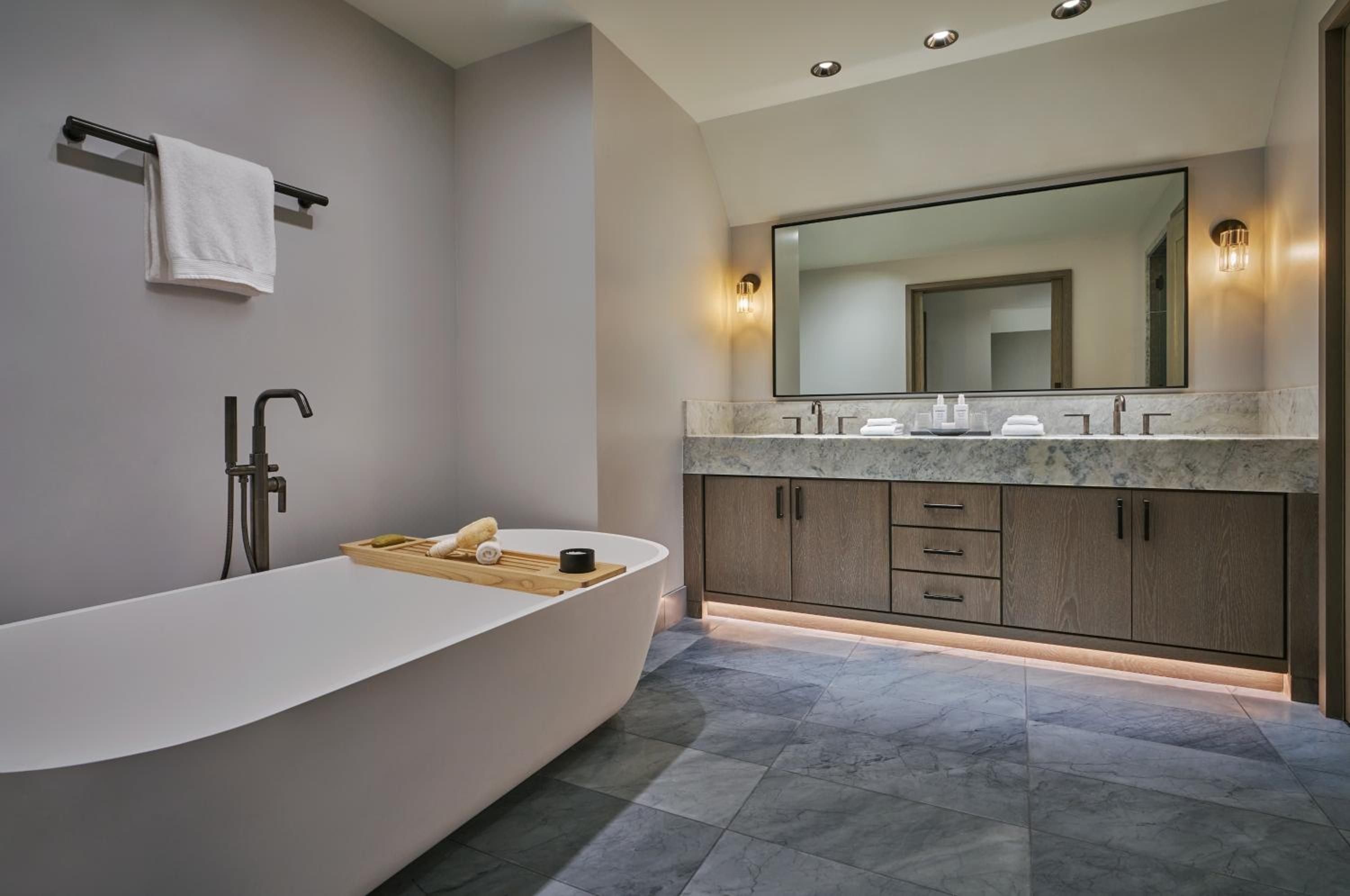Soaking beneath soft recessed lighting, the freestanding tub anchors a spa-like sanctuary where warm wood vanities and marble countertops create mountain luxury.