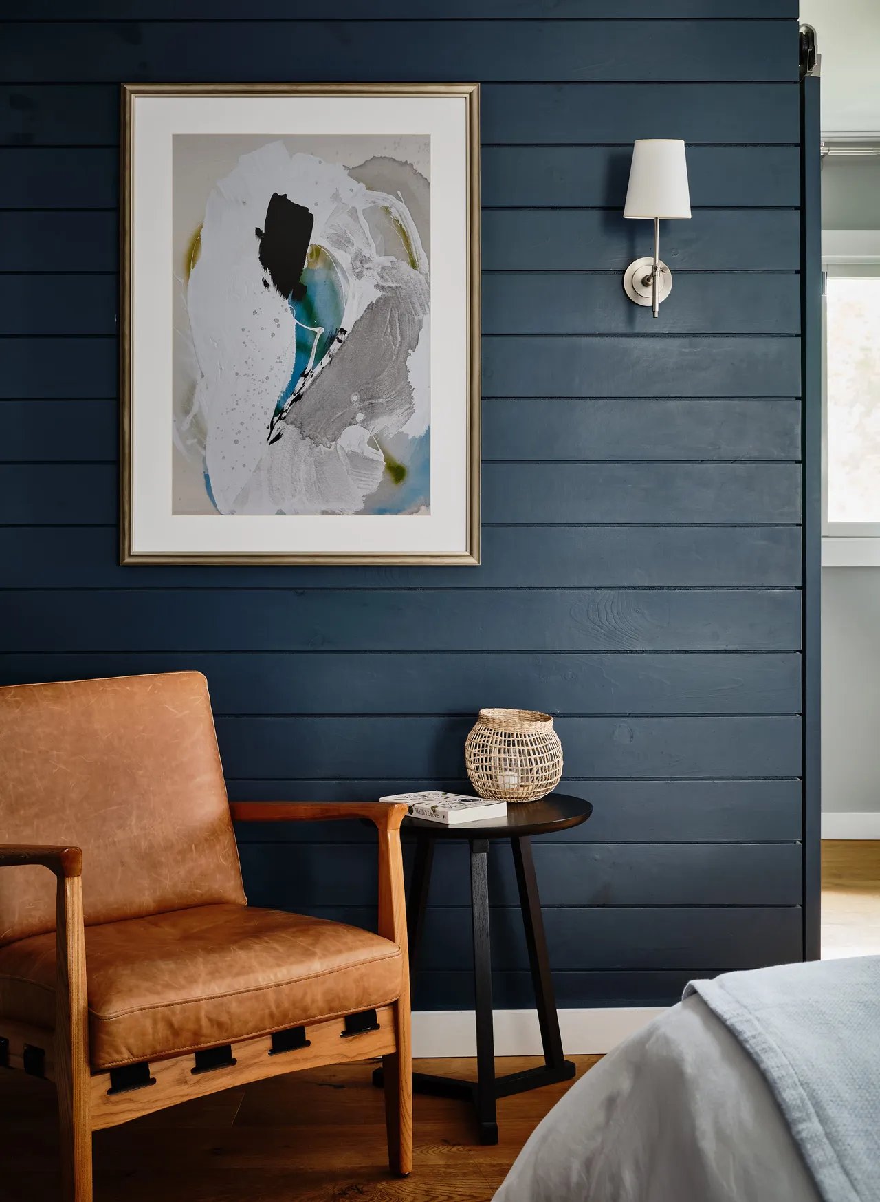 Cognac leather meets moody shiplap walls in thoughtfully curated guest quarters, where abstract art and brass sconces create intimate reading nooks bathed in natural light.