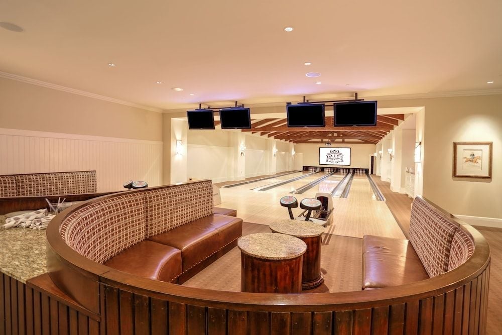 Curved banquette seating and rich wood tones create an intimate viewing area for the resort's private bowling alley, where polished lanes gleam under warm recessed lighting.