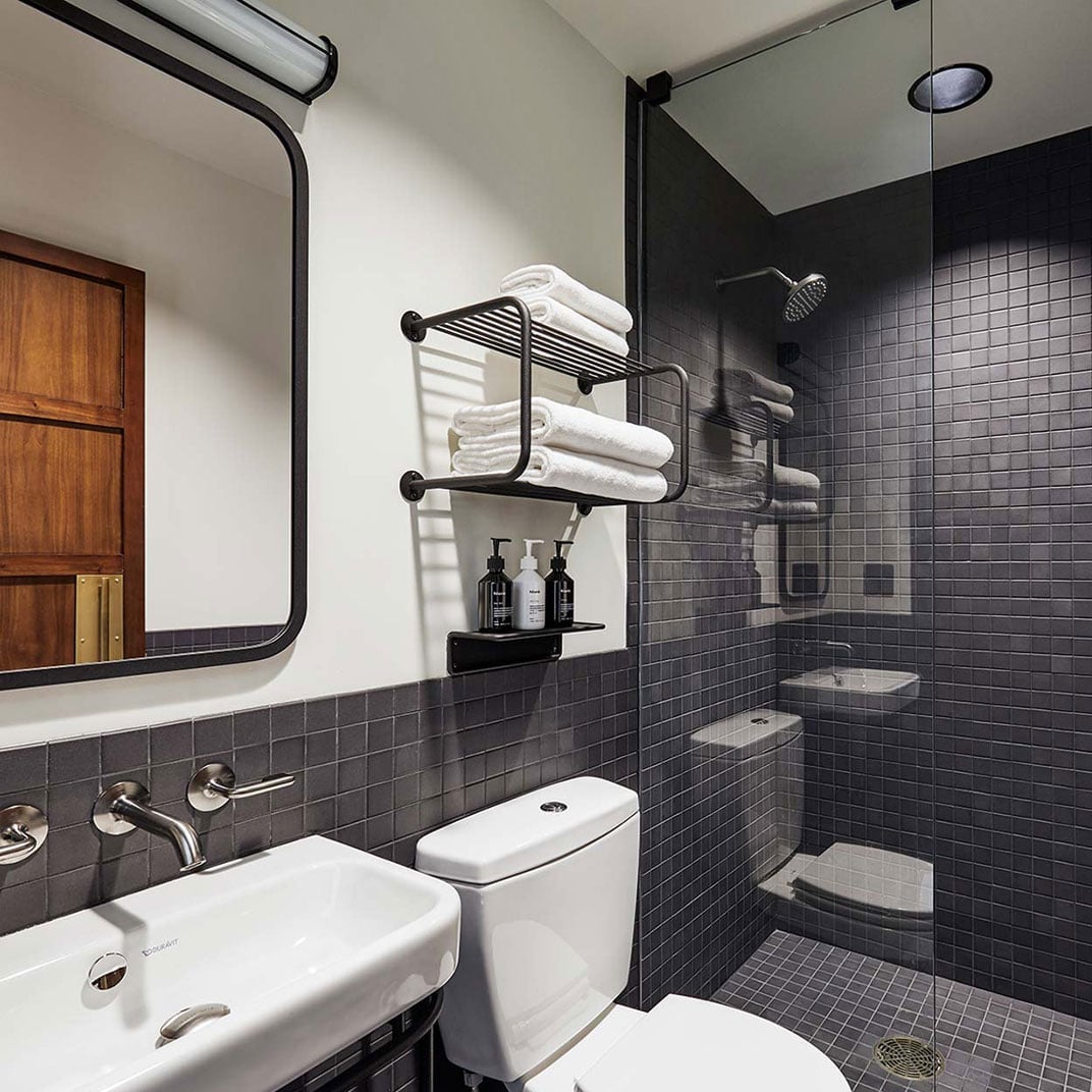 Charcoal subway tiles and industrial-chic black fixtures create a moody, sophisticated bathroom where thoughtful design meets compact functionality in downtown Portland.