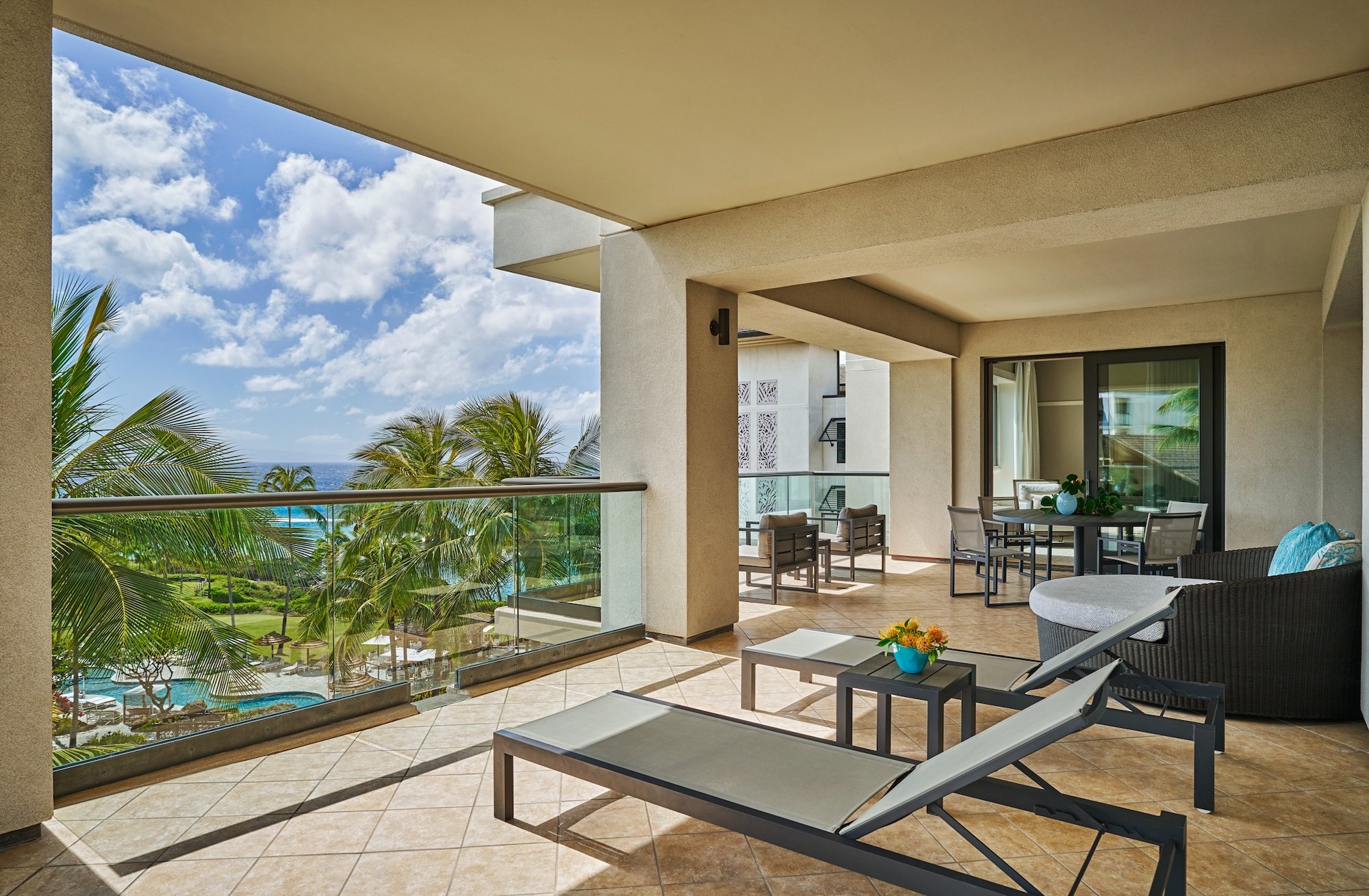 Glass-railed terraces frame sweeping ocean vistas through swaying palms, where contemporary loungers and thoughtful design create an elevated sanctuary above Kapalua's pristine coastline.