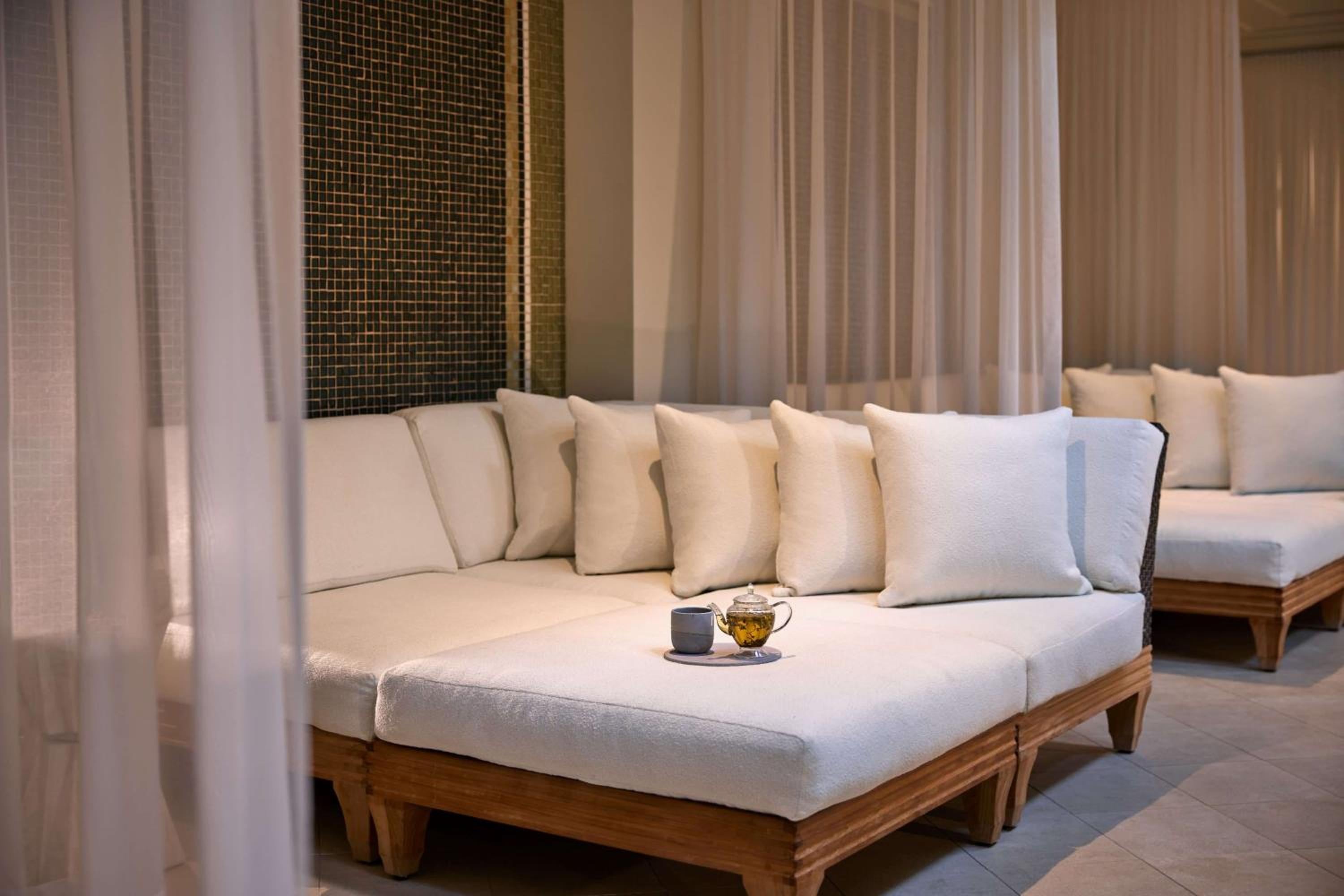 Flowing white curtains frame plush daybeds where afternoon tea awaits, creating an oasis of calm within the spa's serene sanctuary.