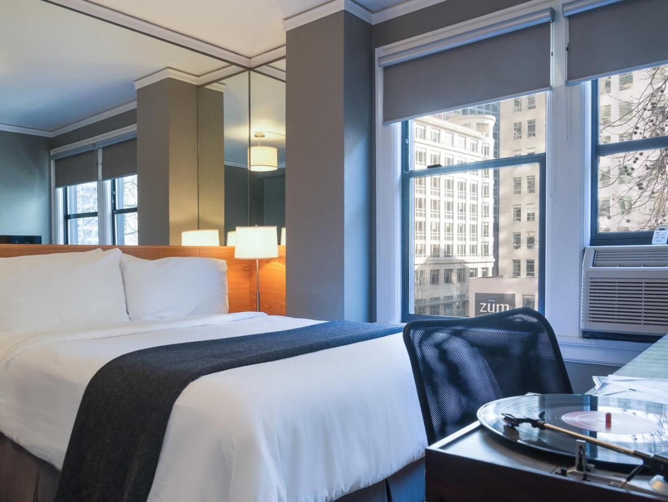 Floor-to-ceiling windows frame Seattle's historic architecture while contemporary furnishings and warm wood accents create an urban sanctuary above the bustling streets.