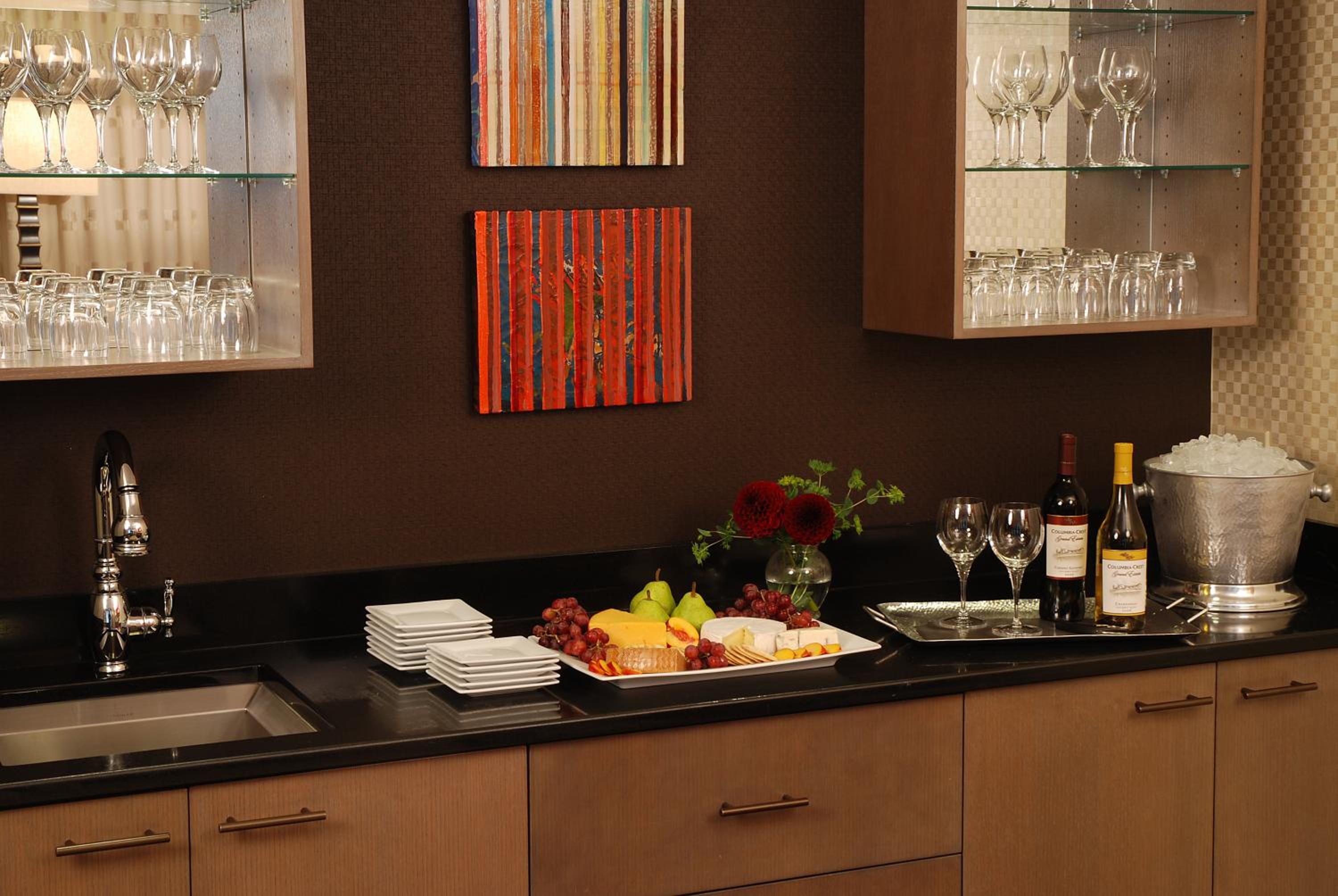 Sleek cabinetry and gleaming glassware create an intimate wet bar where wine pairings and artisanal cheese boards await discerning guests.