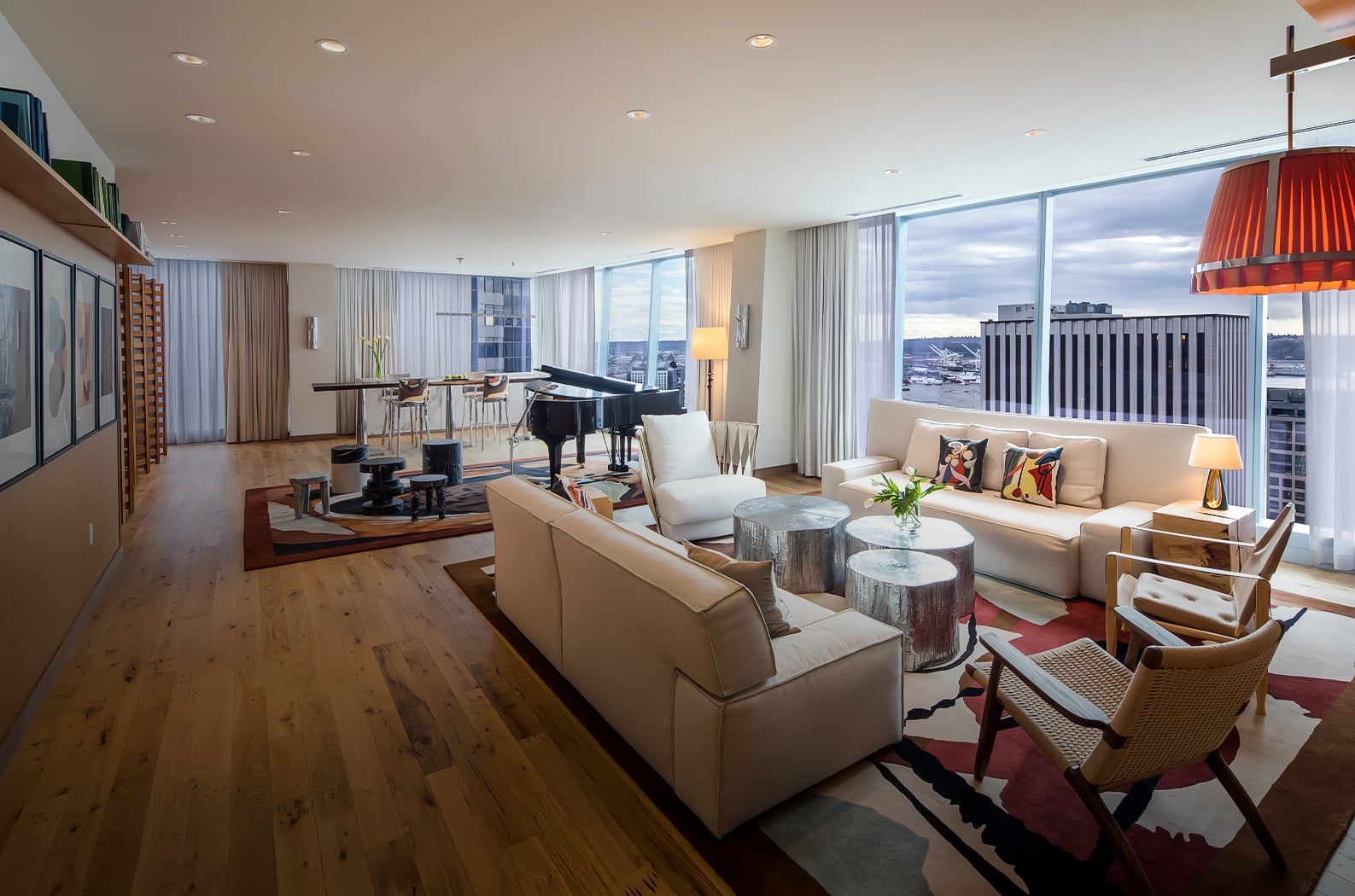 Floor-to-ceiling windows frame Seattle's skyline from this sophisticated suite, where a baby grand piano anchors the open living space with warm wood floors and contemporary furnishings.