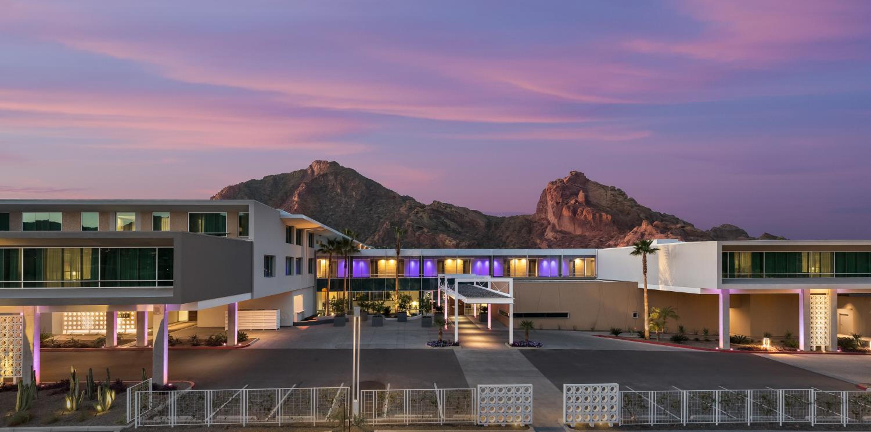 Purple-hued twilight bathes Mountain Shadows Resort's sleek modernist facade, where geometric volumes frame dramatic Camelback Mountain views beyond the illuminated porte-cochère.