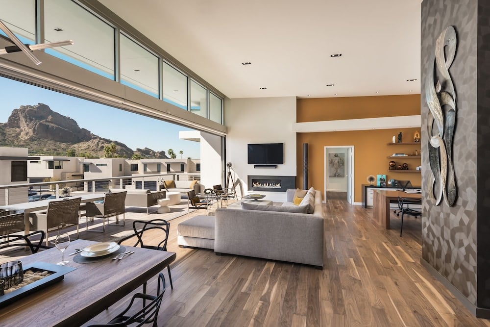 Floor-to-ceiling windows frame Camelback Mountain views from this sophisticated suite, where warm wood floors meet contemporary desert elegance and an inviting outdoor terrace beckons.