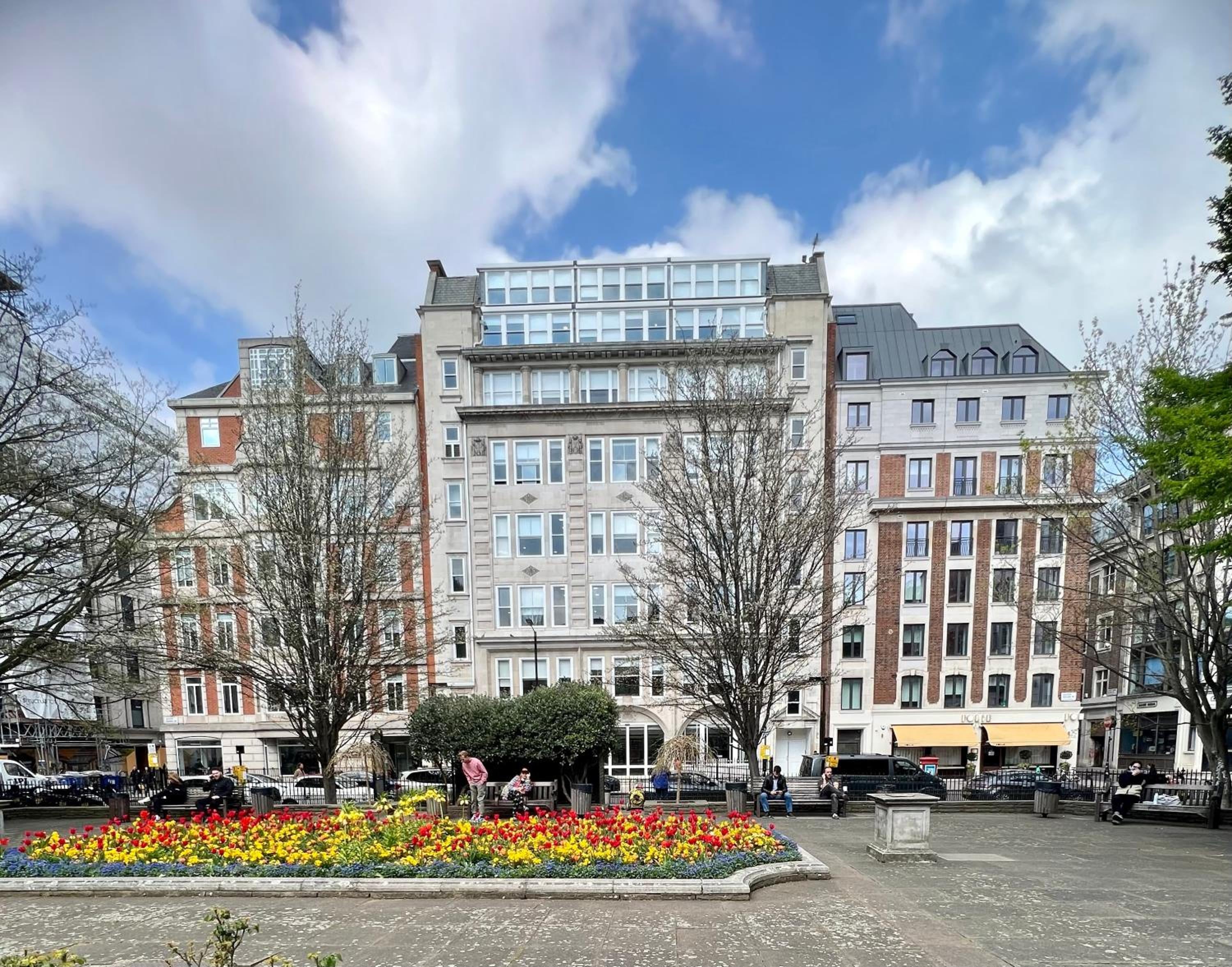 Elegant Victorian facades rise above vibrant flower beds in this charming London square, where cobblestones and leafy trees create an intimate urban sanctuary.