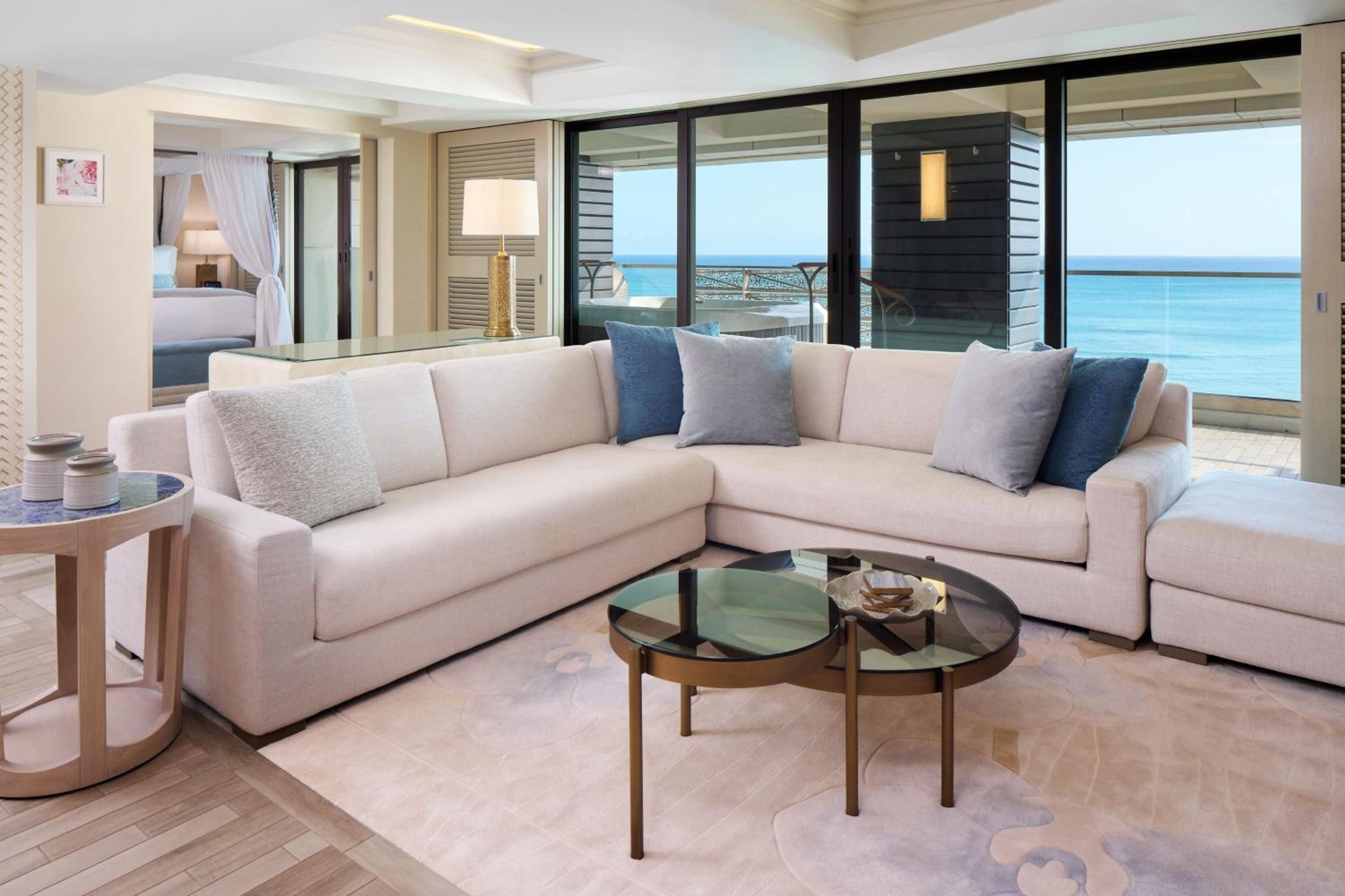 Plush sectional seating and gleaming marble floors frame endless ocean vistas through floor-to-ceiling windows, where azure waters meet contemporary luxury in perfect harmony.
