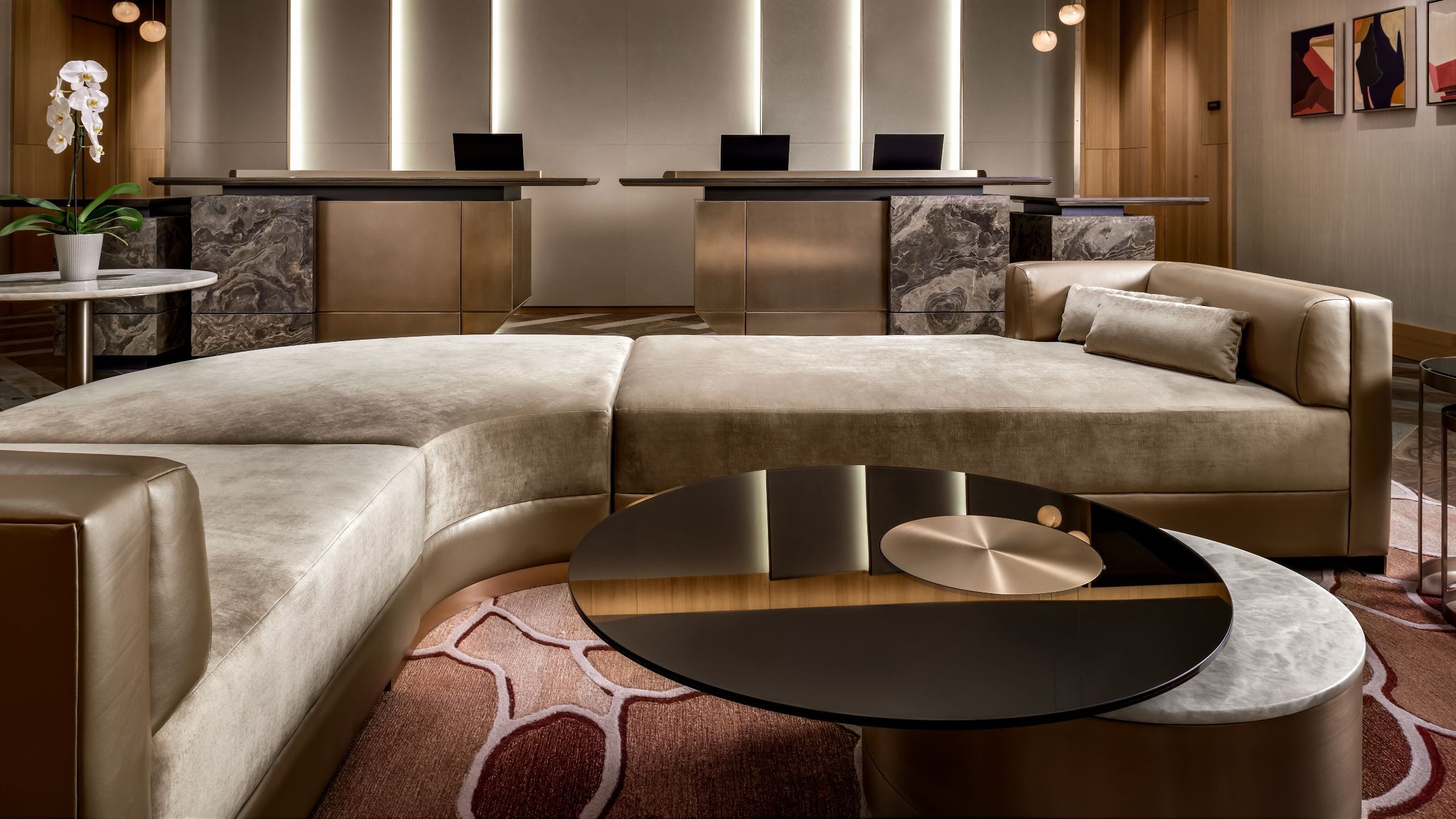 Curved velvet banquettes embrace a sculptural coffee table in the hotel's sophisticated lounge, where warm lighting and marble accents create an intimate urban sanctuary.