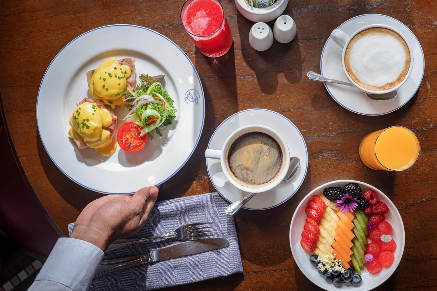 Expertly crafted eggs Benedict with silky hollandaise arrive alongside artfully arranged tropical fruits, while perfectly pulled espresso and fresh orange juice complete this indulgent morning ritual.