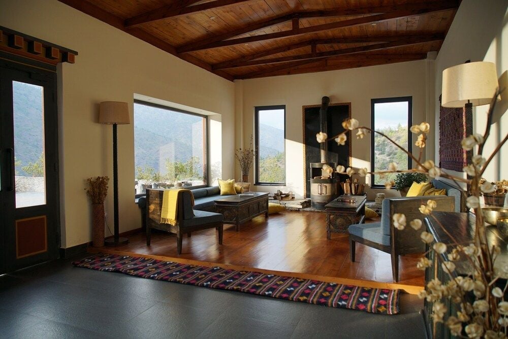 Exposed timber beams frame mountain vistas through floor-to-ceiling windows, while handwoven textiles and mid-century furniture create an intimate sanctuary above Thimphu's valleys.