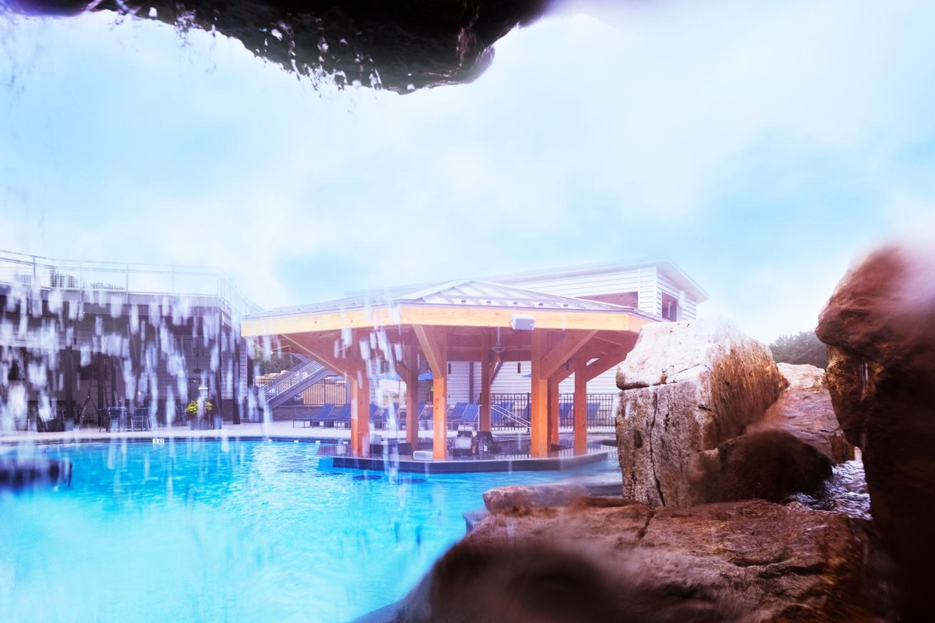 Steam rises from mineral-rich waters while snow blankets the mountainside pavilion, creating an otherworldly contrast between warm springs and winter's embrace.