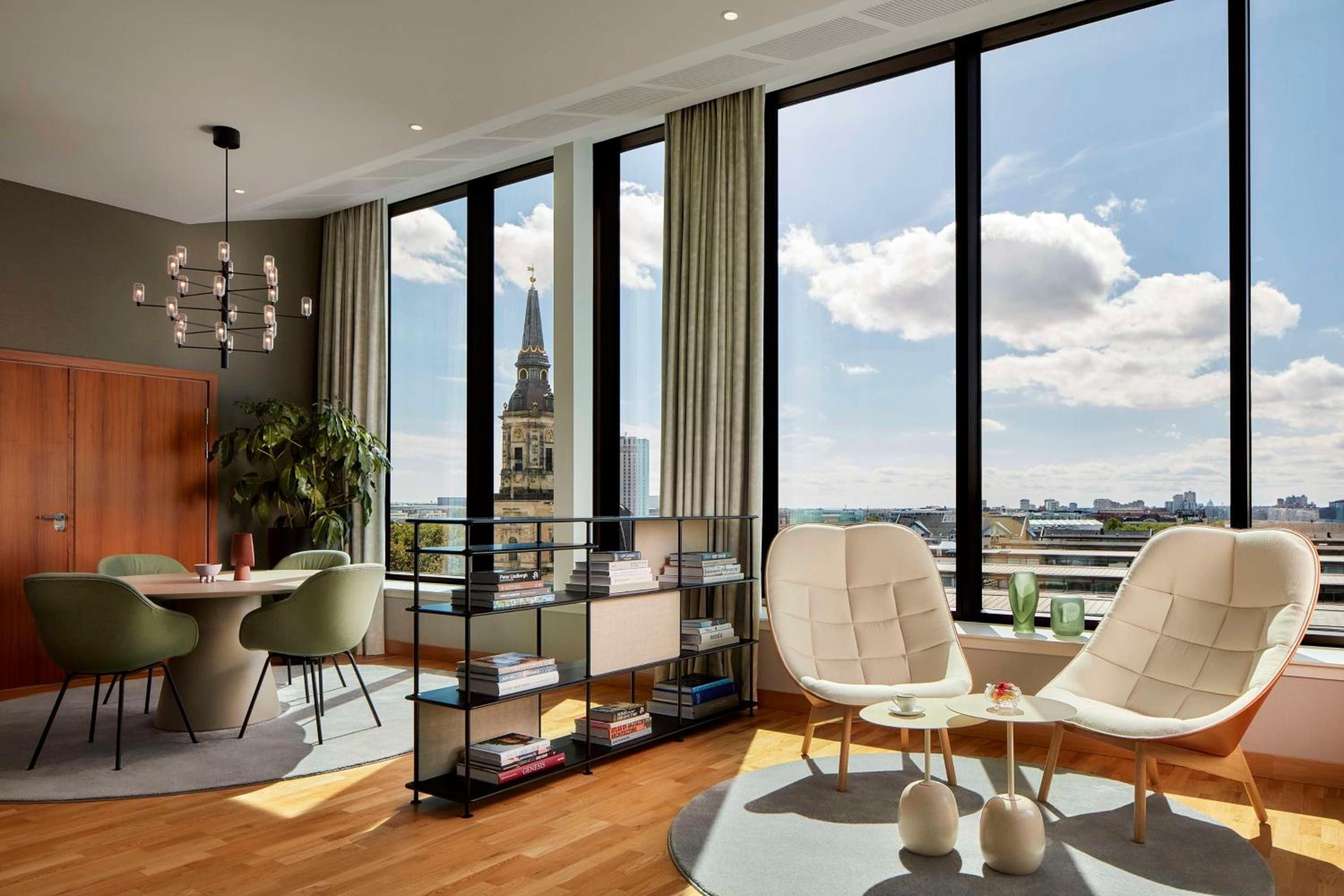 Floor-to-ceiling windows frame Copenhagen's historic spires while mid-century furnishings and warm wood floors create an effortlessly sophisticated urban retreat above the Danish capital.