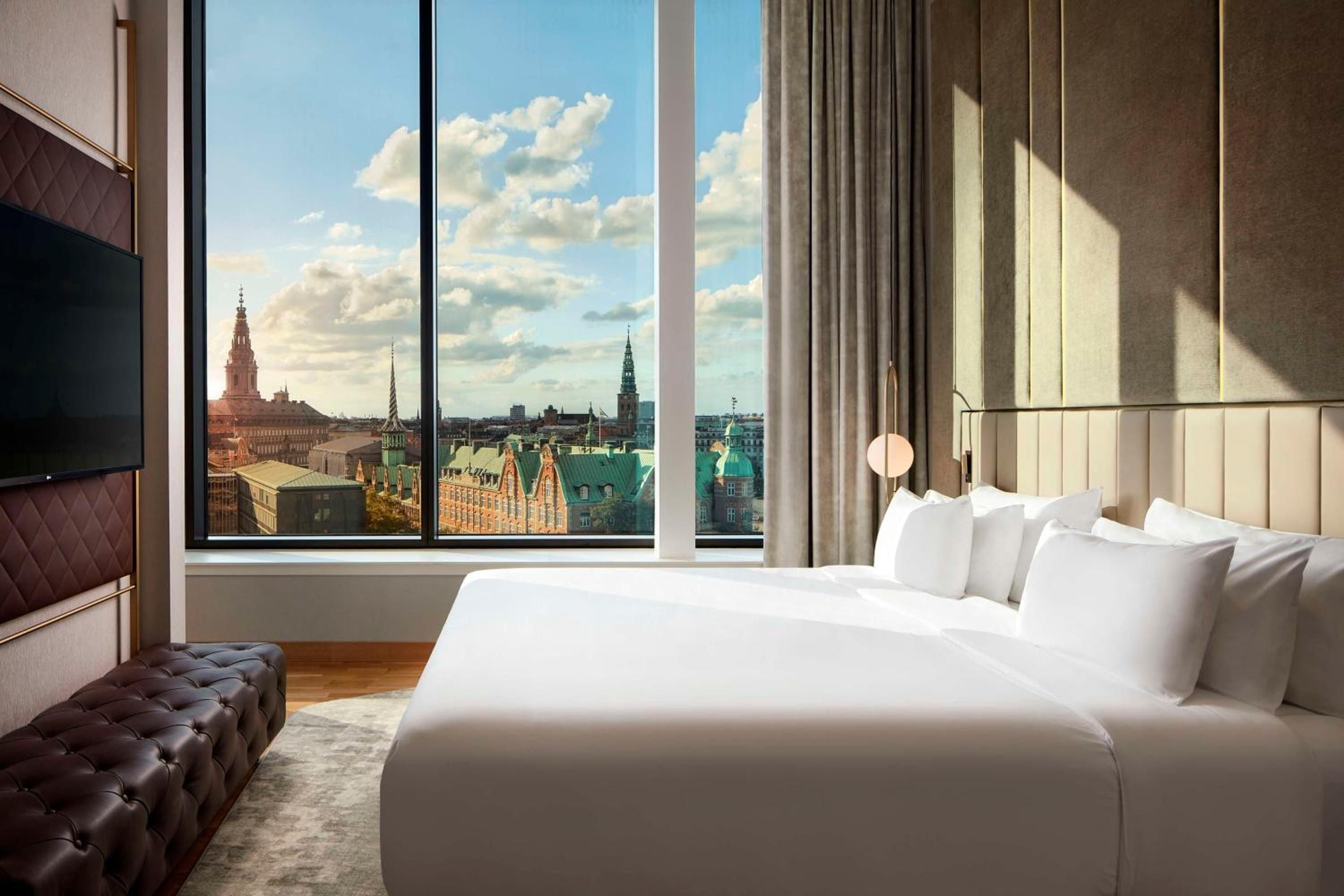 Floor-to-ceiling windows frame Copenhagen's historic spires and copper rooftops from this elegantly appointed suite, where crisp linens meet Nordic design sophistication.
