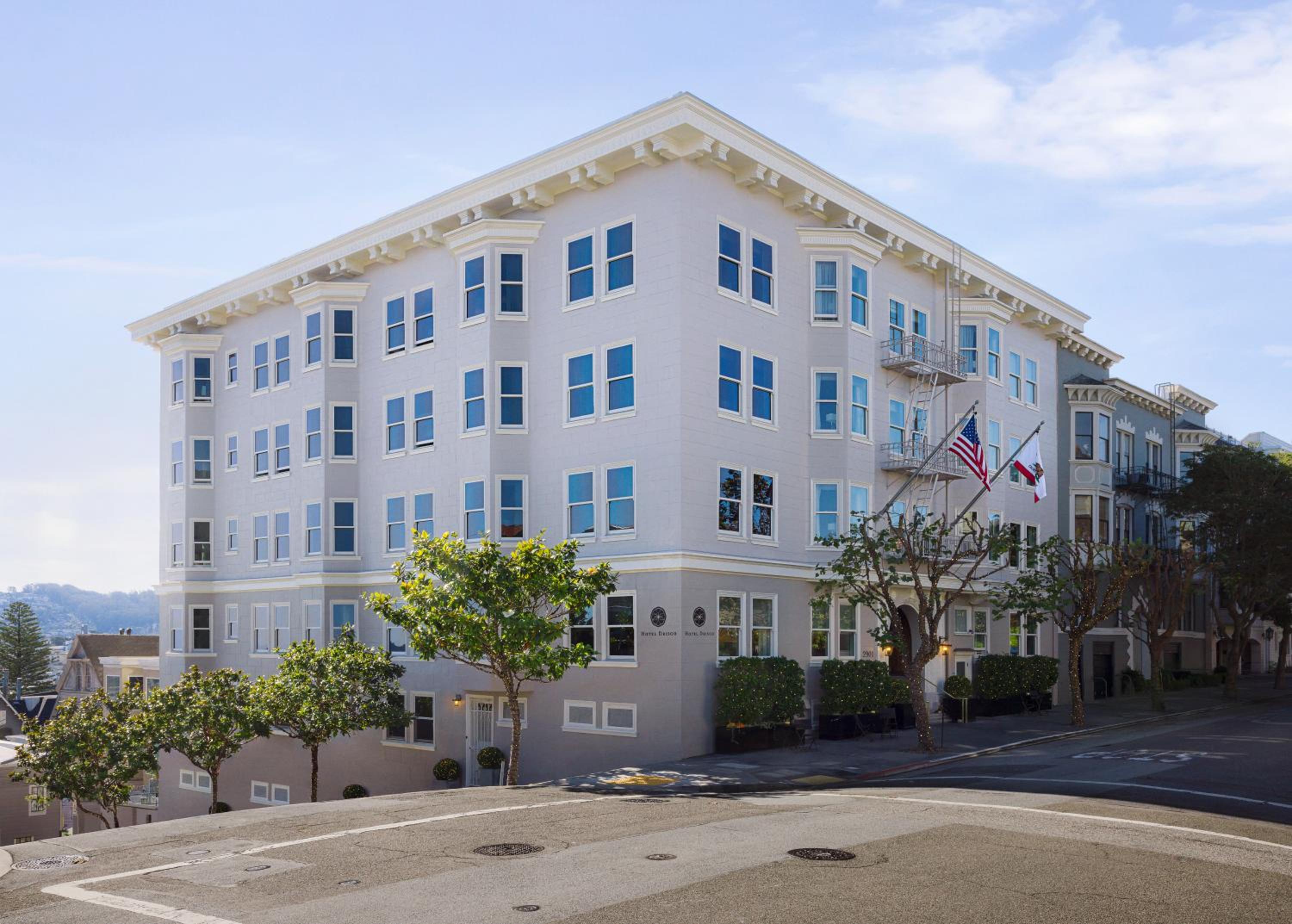Classic Edwardian architecture commands a prestigious Pacific Heights corner, where ornate cornices and pristine white facades reflect San Francisco's golden afternoon light across tree-lined streets.