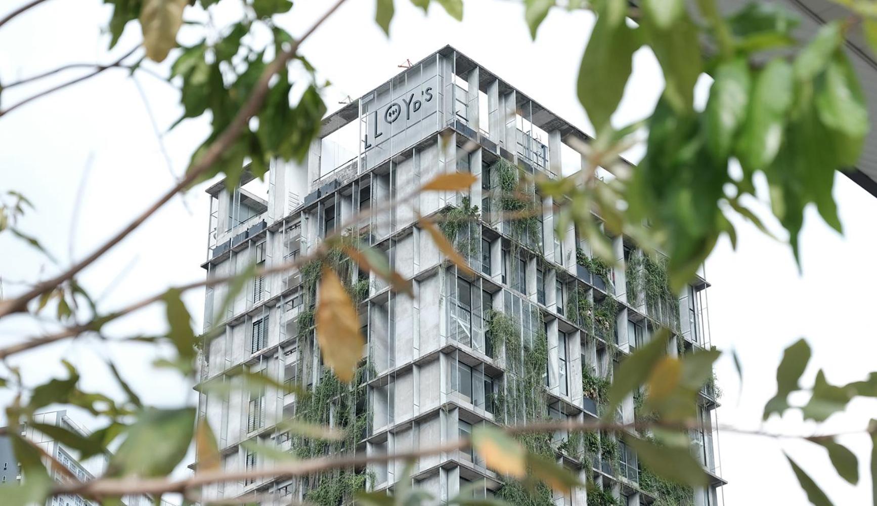 Verdant foliage frames Lloyd's Inn's striking concrete tower, where cascading greenery softens the brutalist facade and creates an unexpected urban oasis in bustling Kuala Lumpur.
