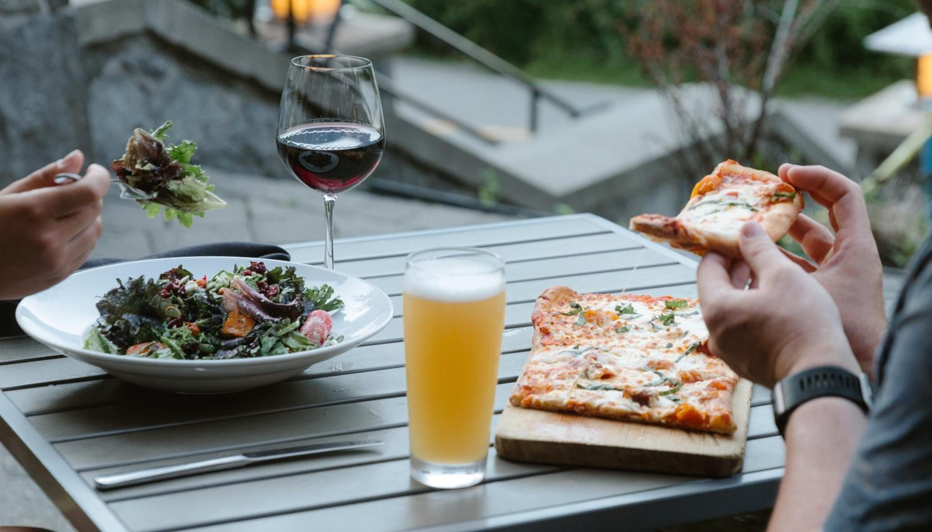 Crisp mountain air enhances al fresco dining as guests savor wood-fired pizza and local greens, wine glasses catching golden hour light on weathered timber tables.