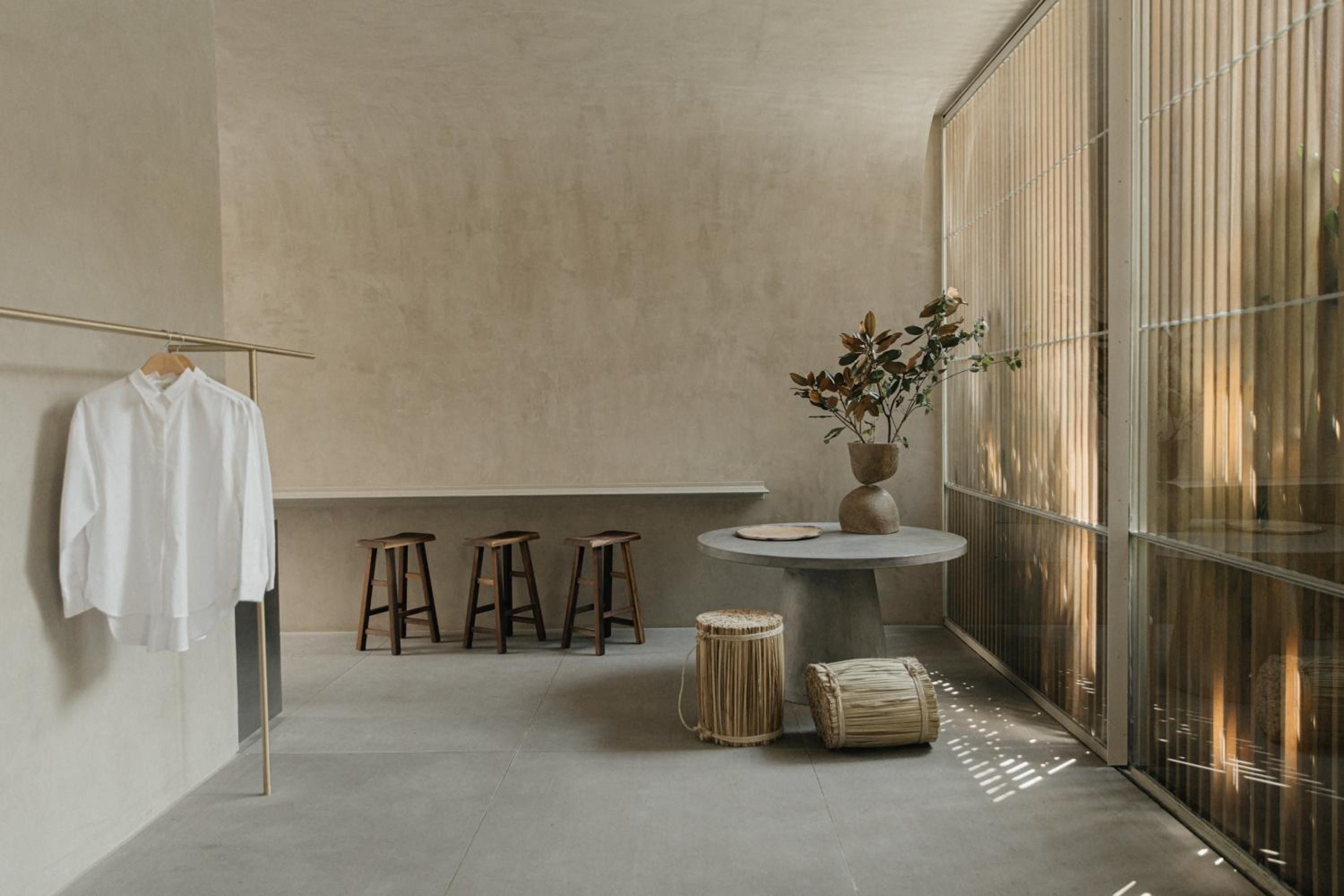 Natural light filters through bamboo screens, casting gentle shadows across minimalist surfaces where woven baskets and earthen vessels create quiet harmony in this serene living space.
